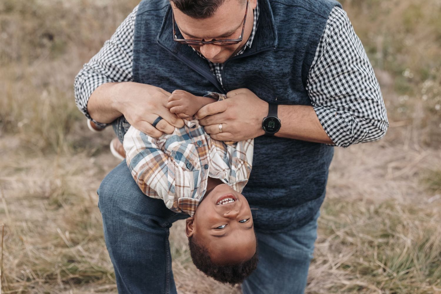 A playful moment captured between parent and child playing upside down outdoors.