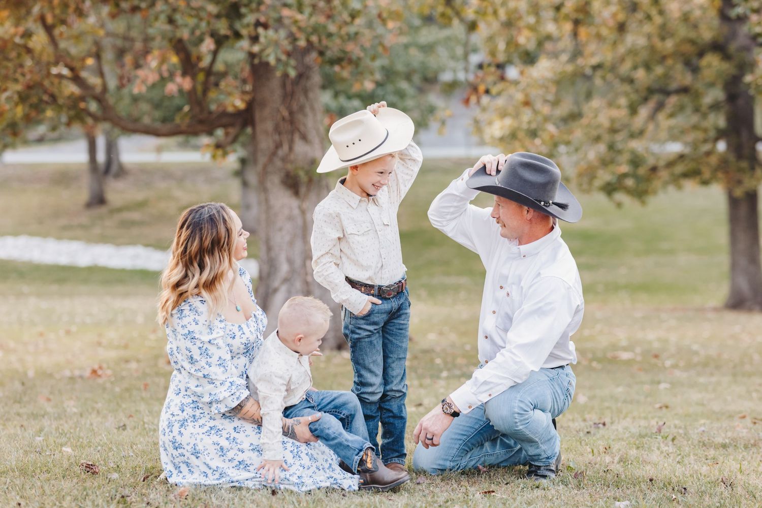 An intimate family scene photographed outdoors with fall foliage in the background.