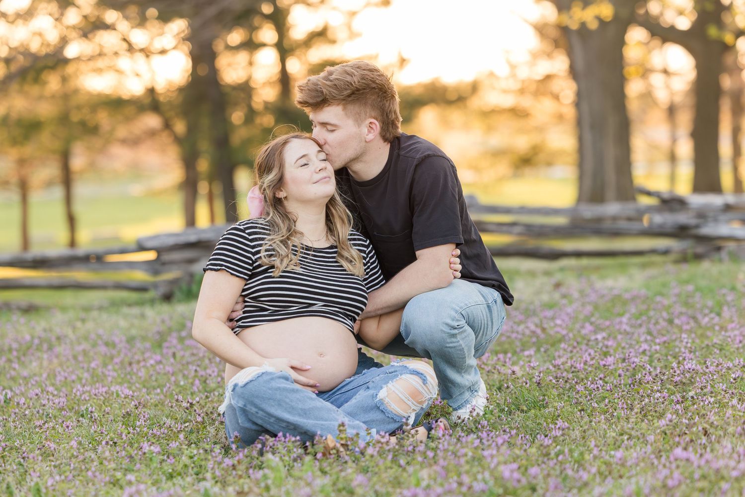 A couple shares an intimate moment while sitting in a wildflower field during golden hour sunset.