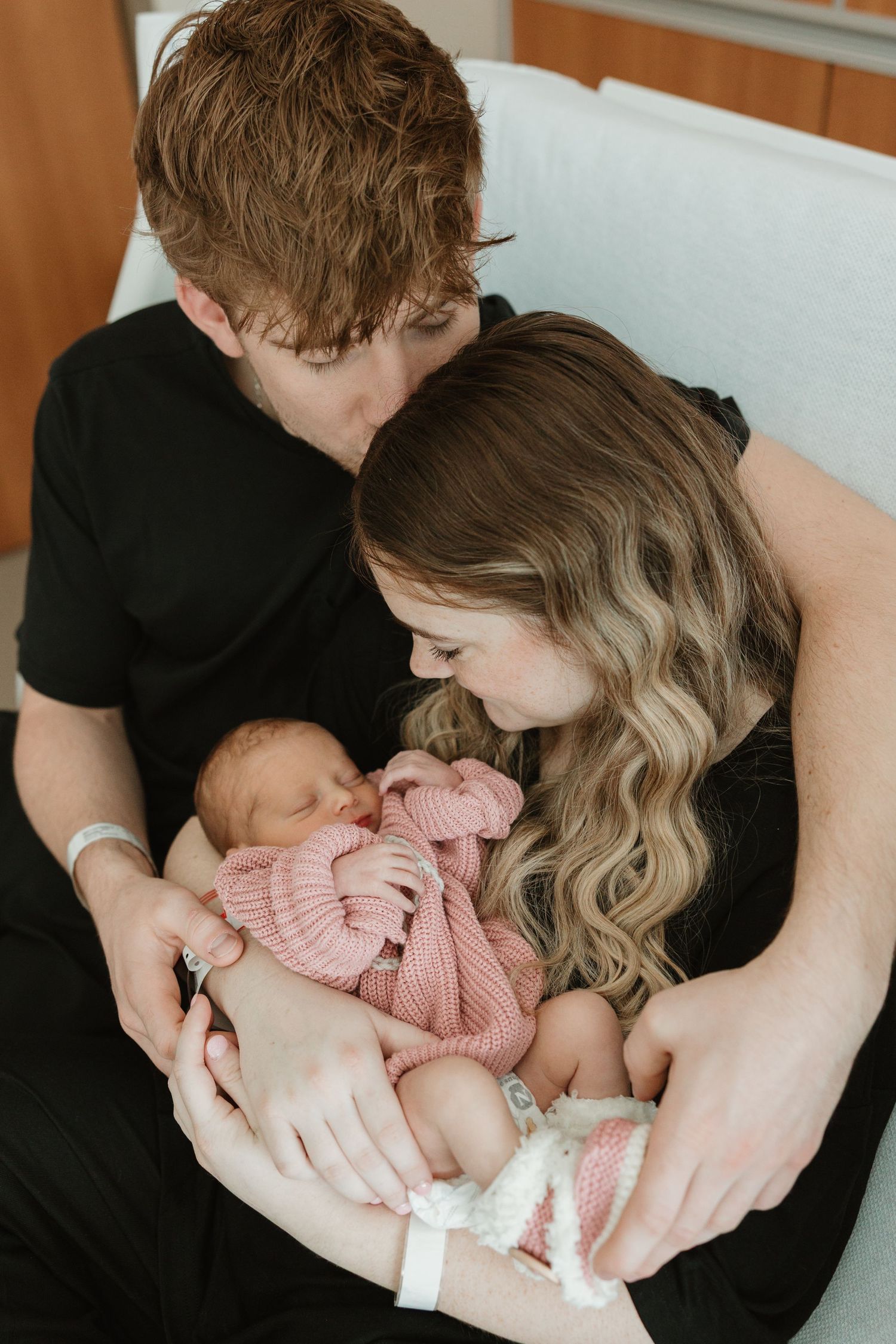 A series of intimate photos showing tender moments with a newborn baby in a pink outfit being held and cradled.