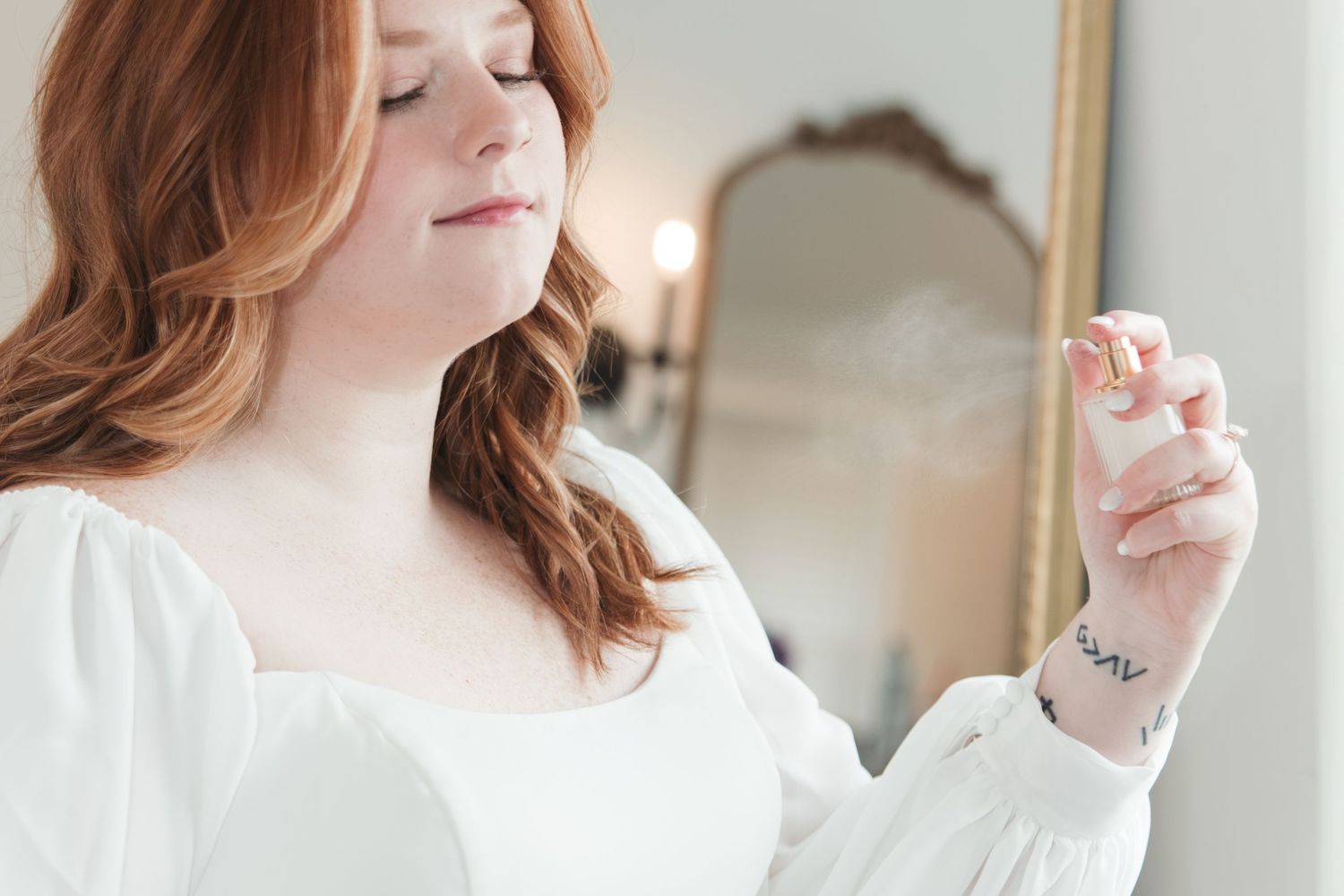 Close-up detail of person in white long-sleeve dress with small wrist tattoo.