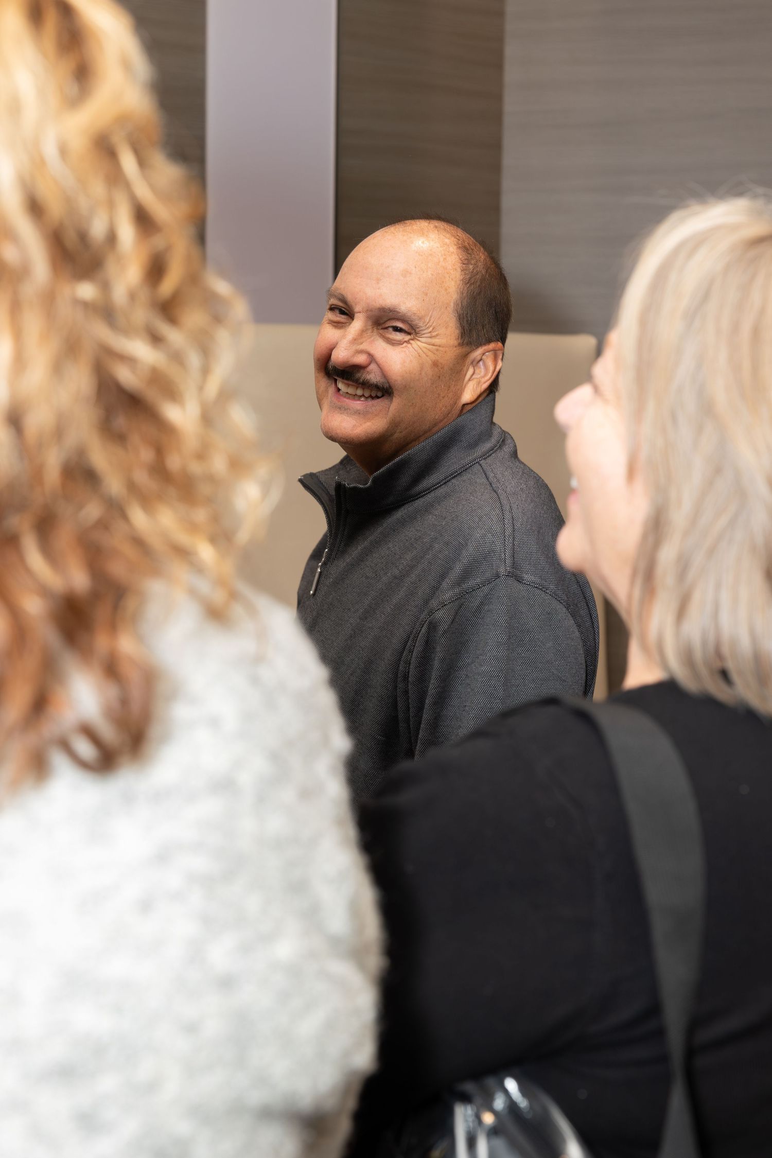 Casual conversation between guests at an indoor corporate celebration.