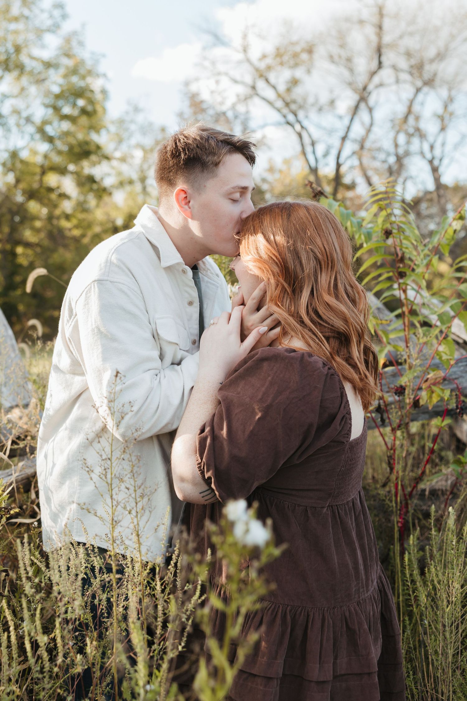 Intimate portrait of a couple about to kiss in a natural outdoor setting with wild foliage.