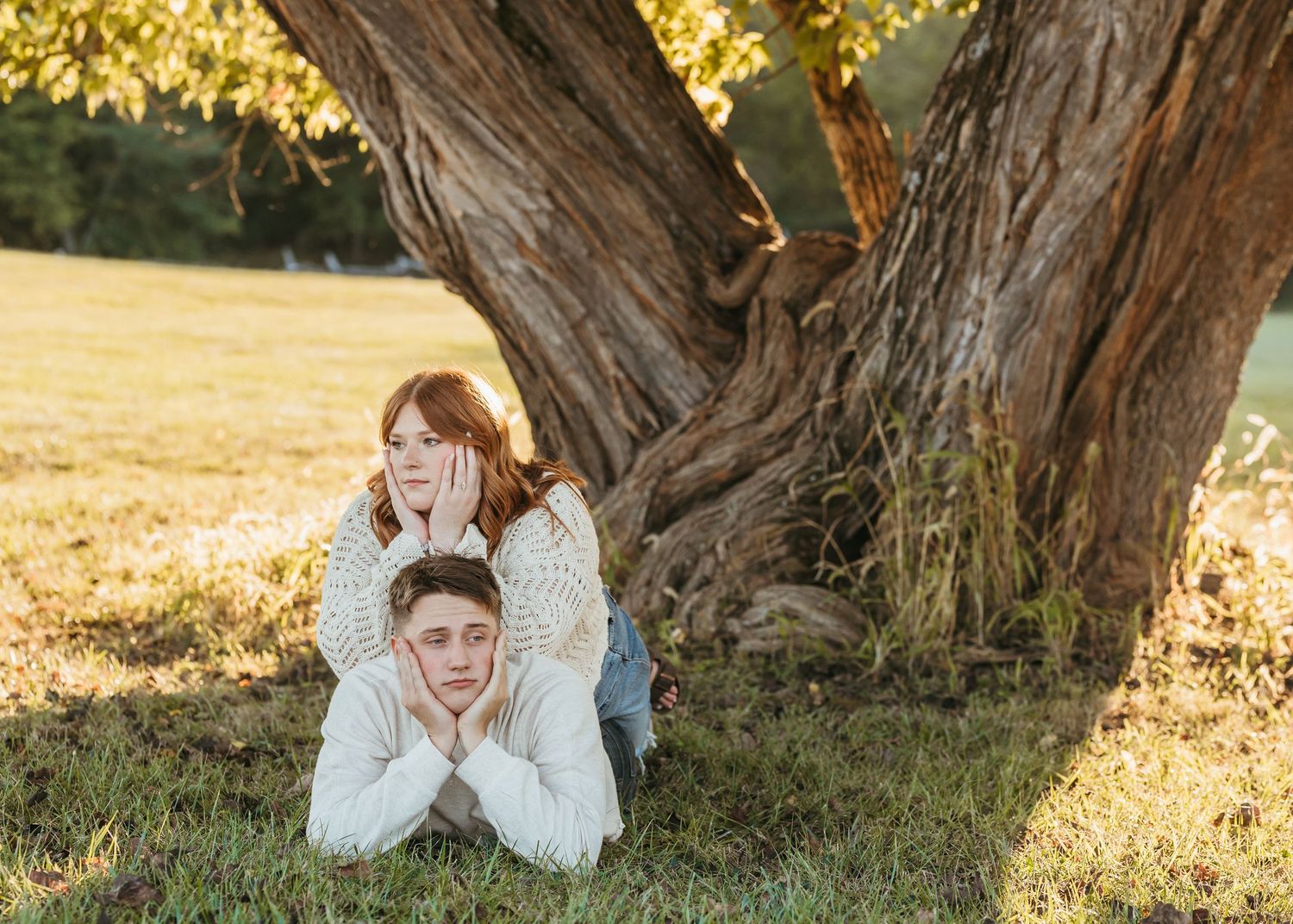 A playful outdoor photoshoot by a large tree trunk in golden afternoon sunlight.