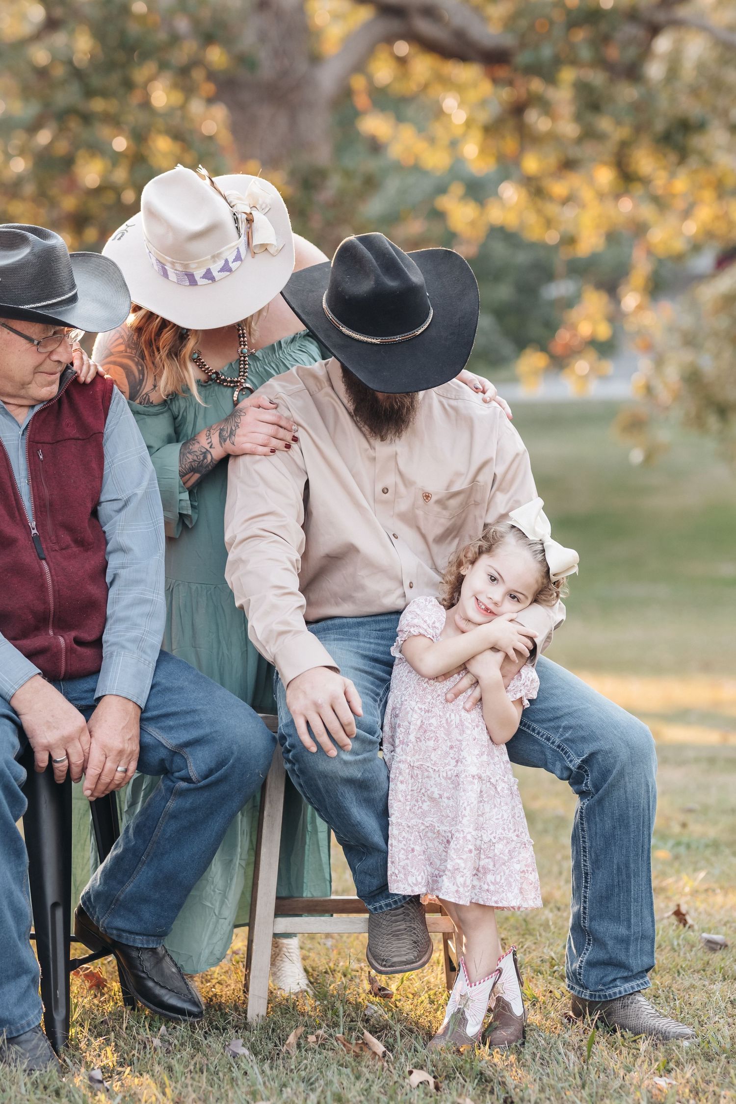 A heartwarming family moment captured outdoors with western attire and cowboy hats during golden hour.