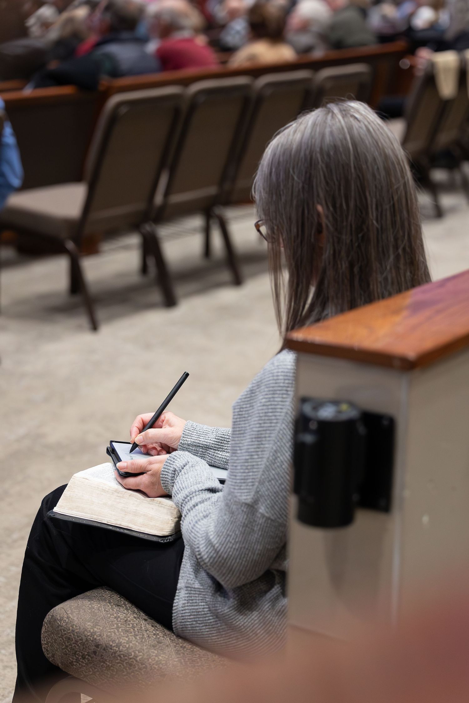 Person taking notes in a notebook during a church service or conference.