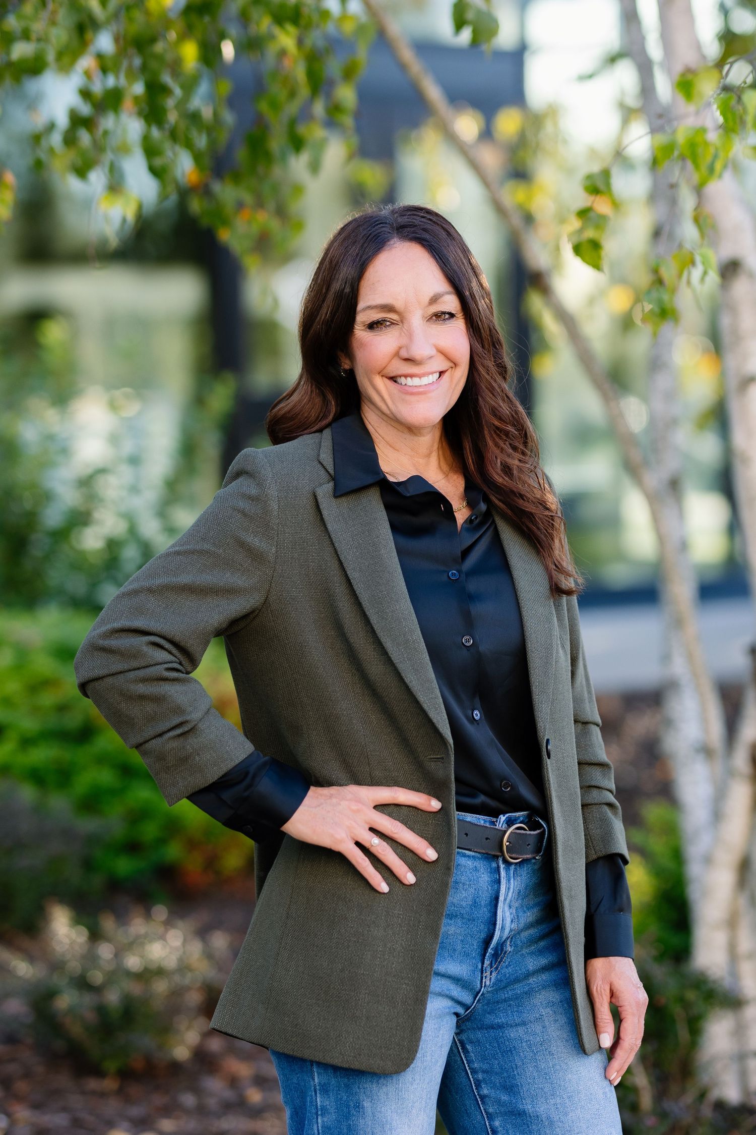 Professional outdoor portrait featuring olive blazer, black shirt and denim in natural setting.