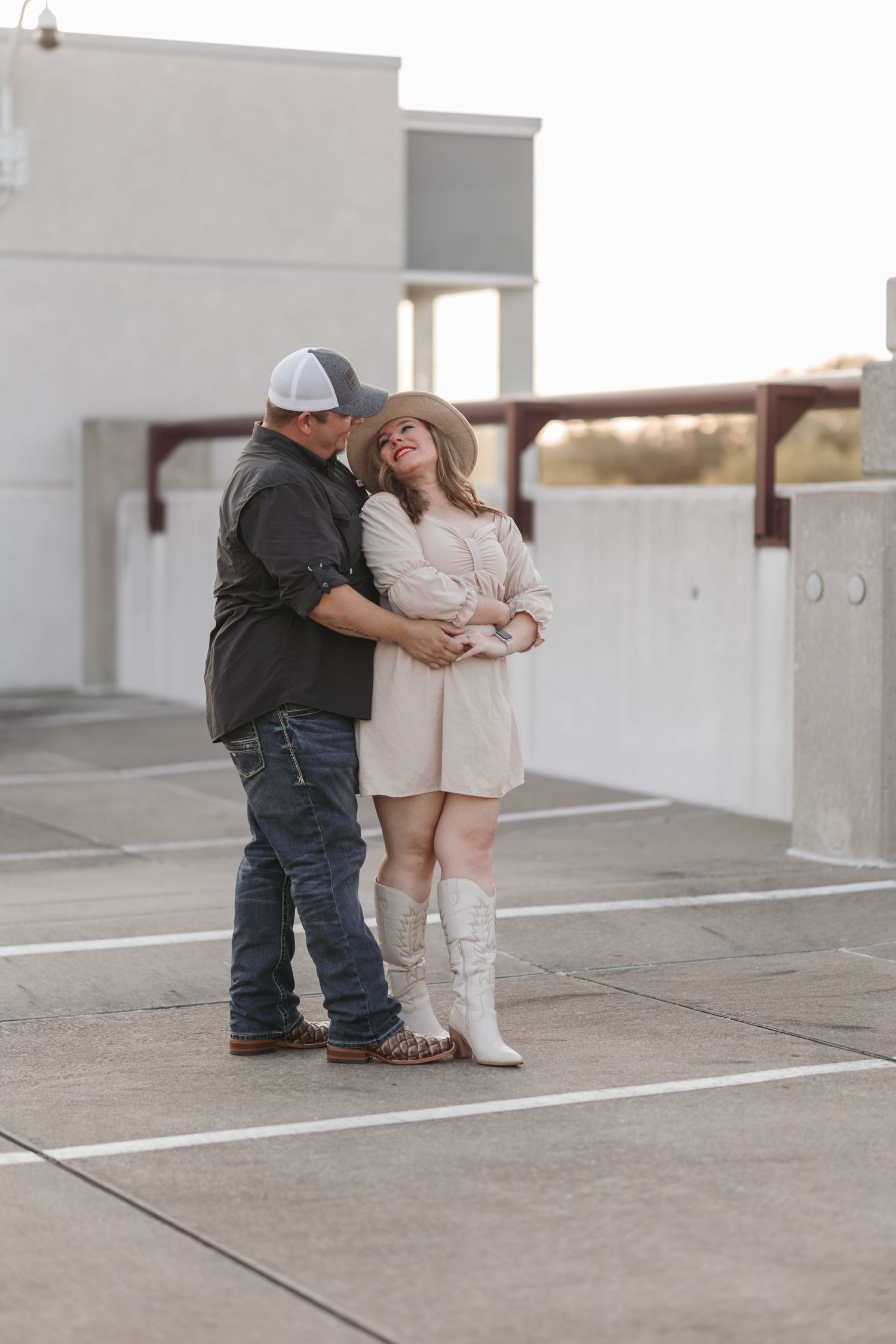 Couple in coordinating outfits sharing an intimate moment in a parking structure.