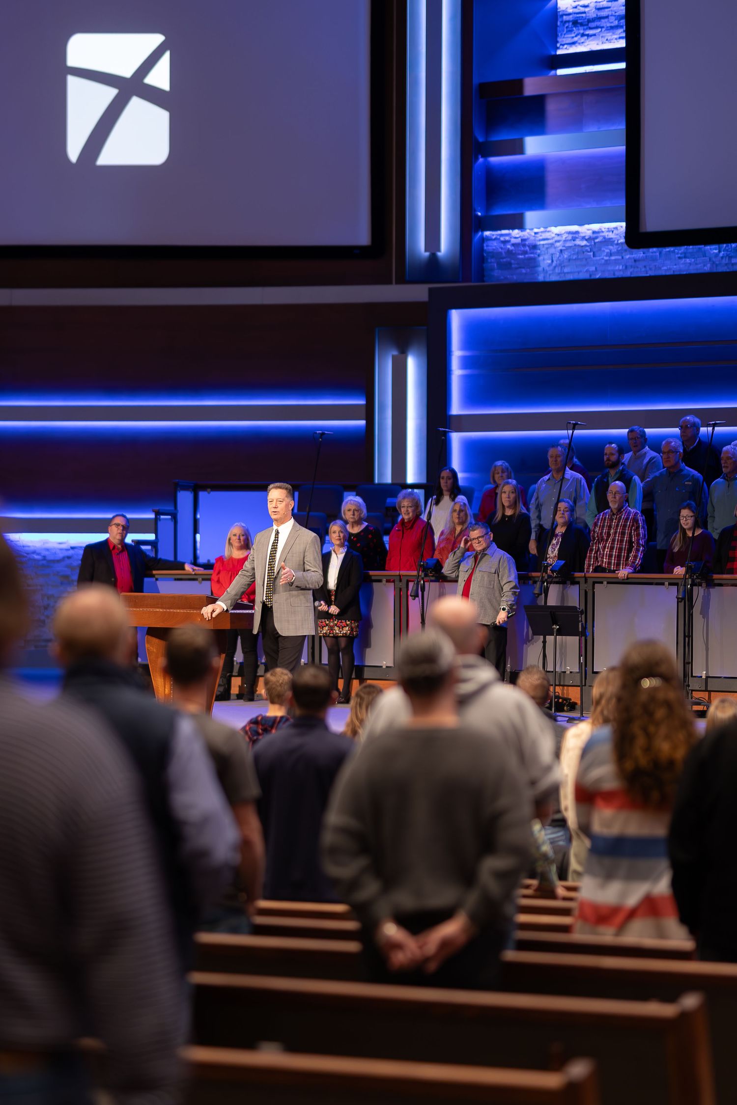 Modern church service with blue LED lighting and large projection screens.