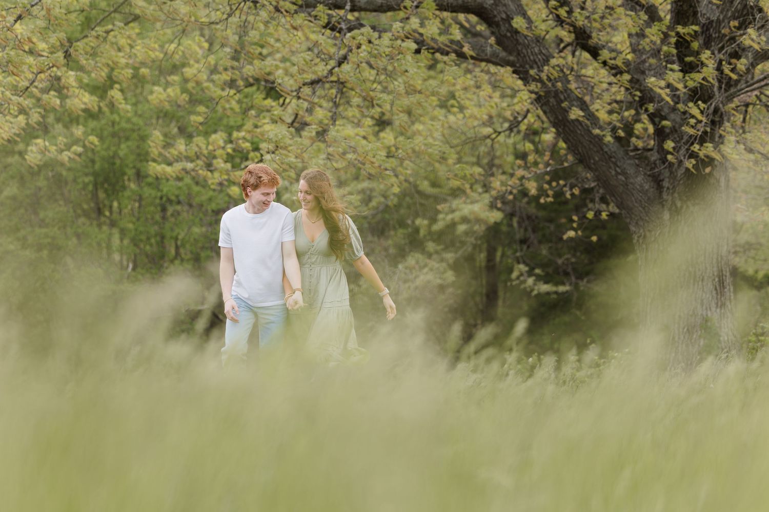 A warm candid family moment captured in a blurry outdoor garden setting with sunlit greenery and foliage.