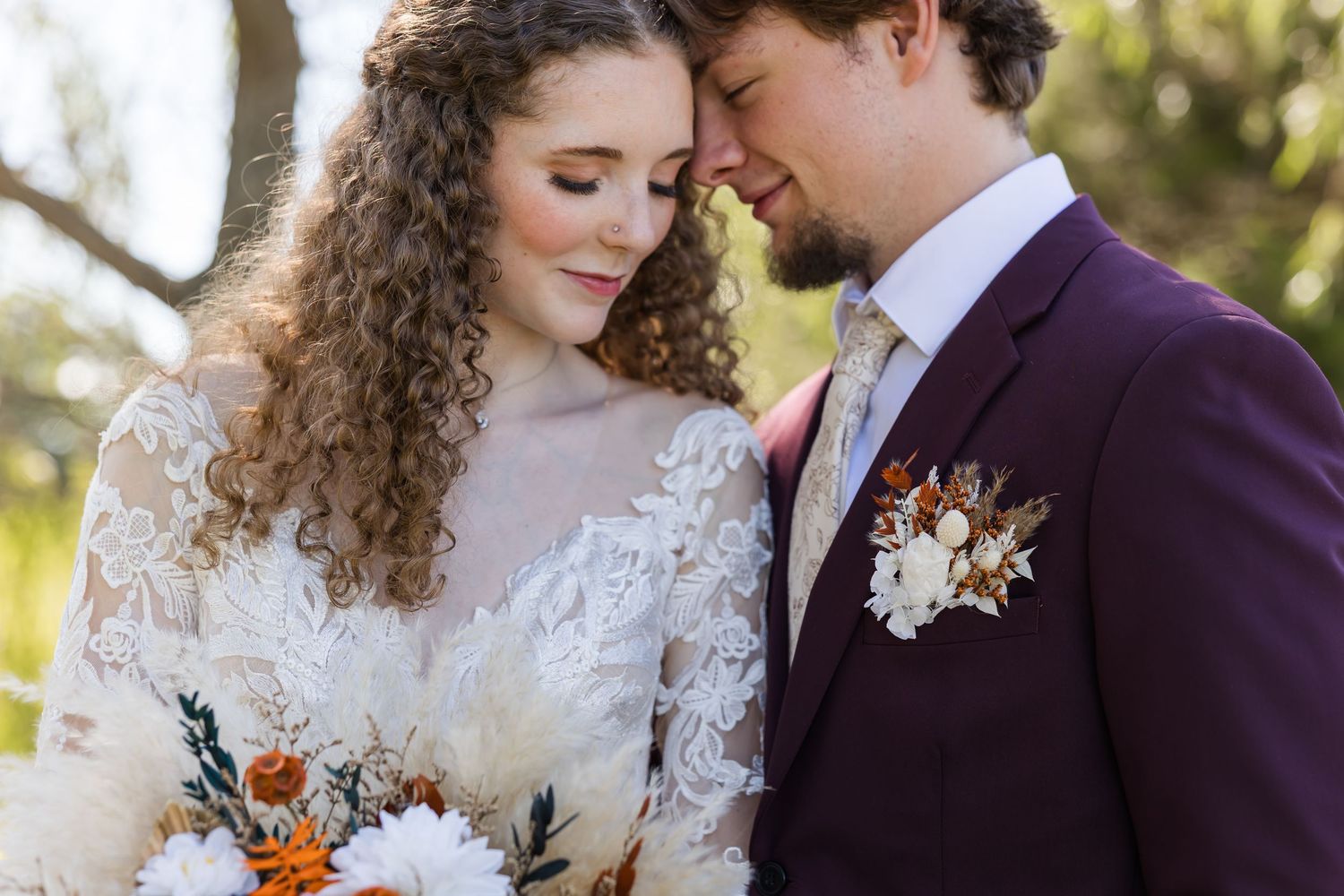 A couple shares an intimate moment during their autumn wedding ceremony surrounded by fall foliage and florals.