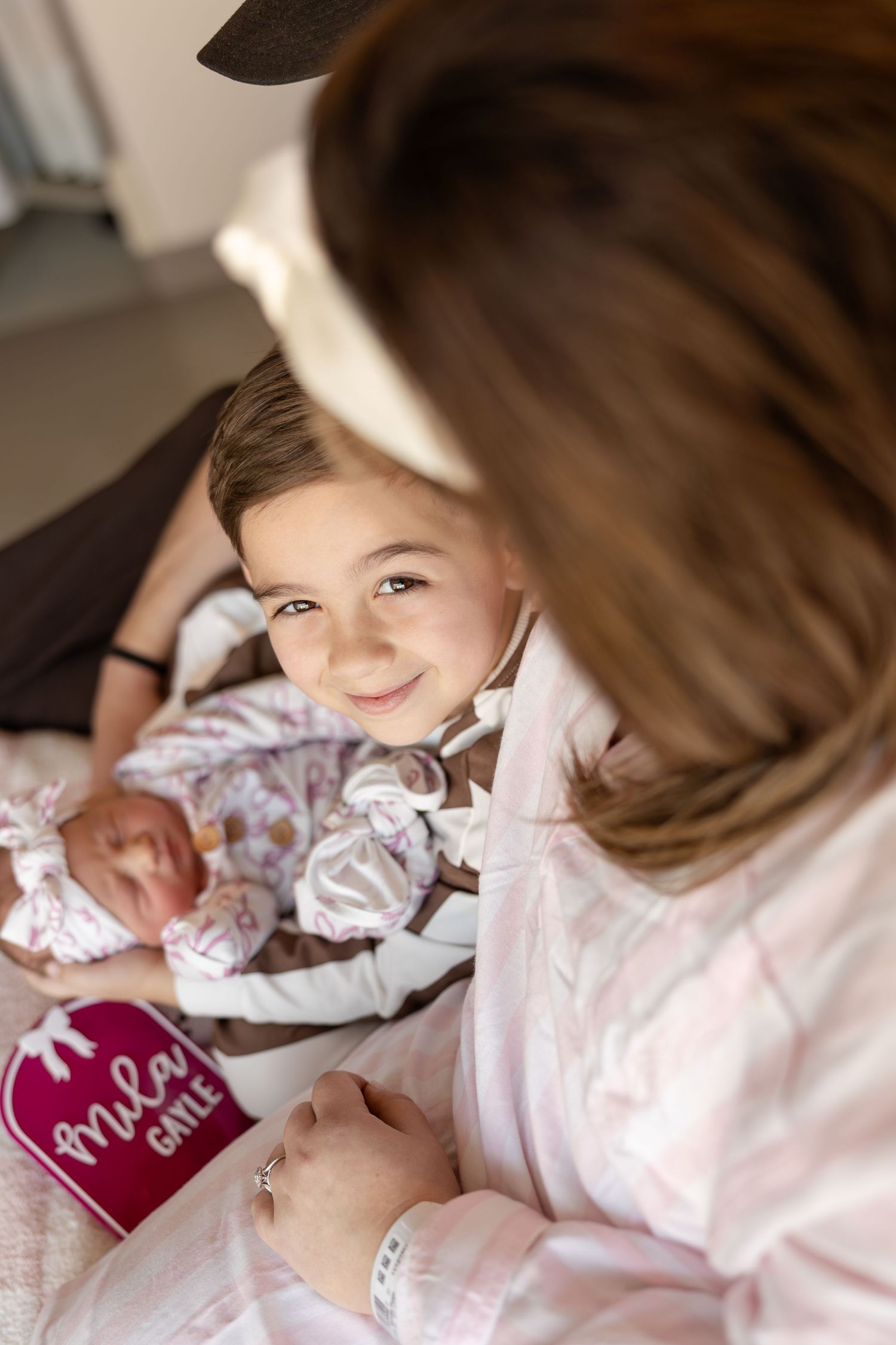 Sweet moment showing family bonding with newborn baby in hospital room with pink heart sign visible.