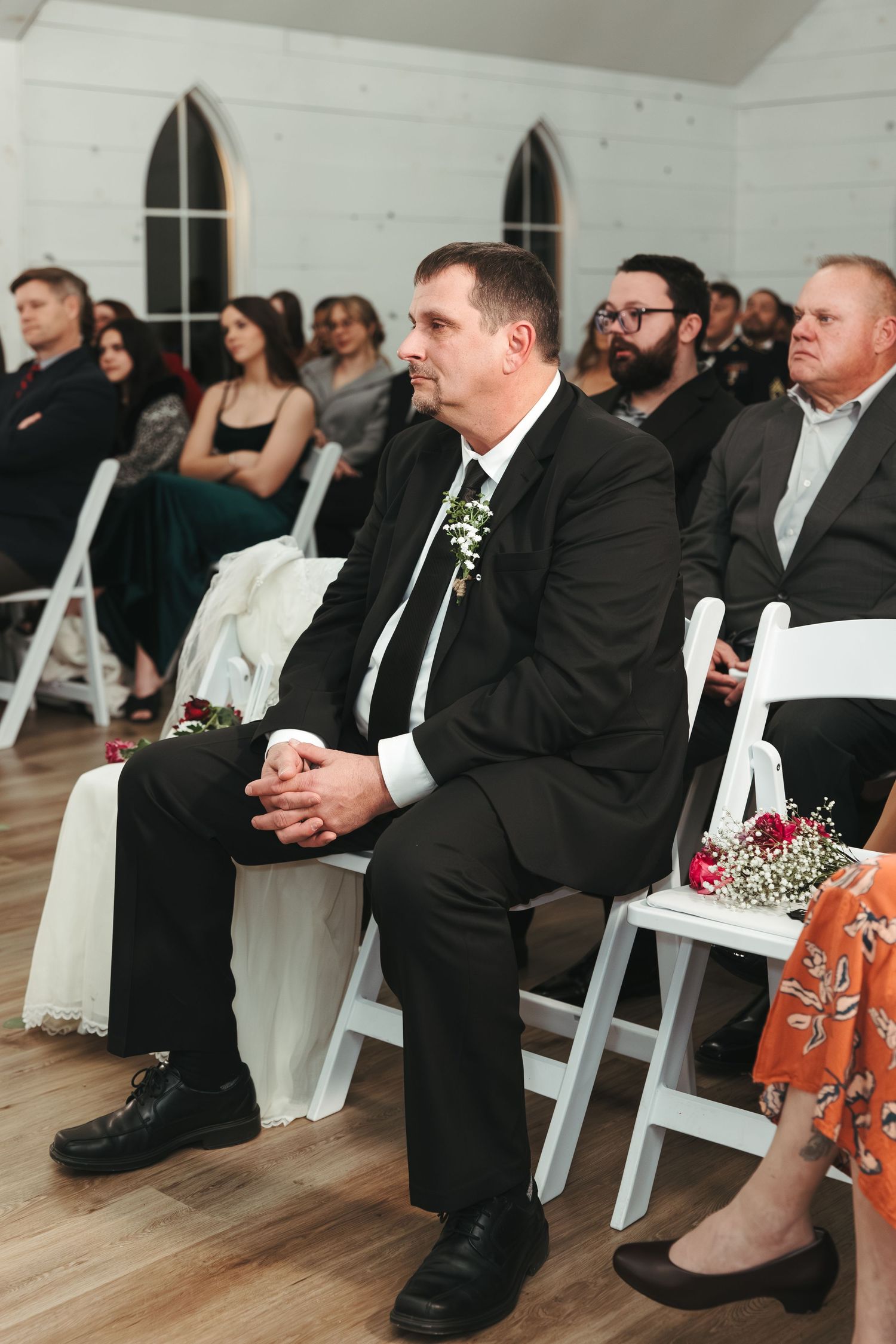Guests watching attentively during an indoor wedding ceremony in a chapel with gothic windows.