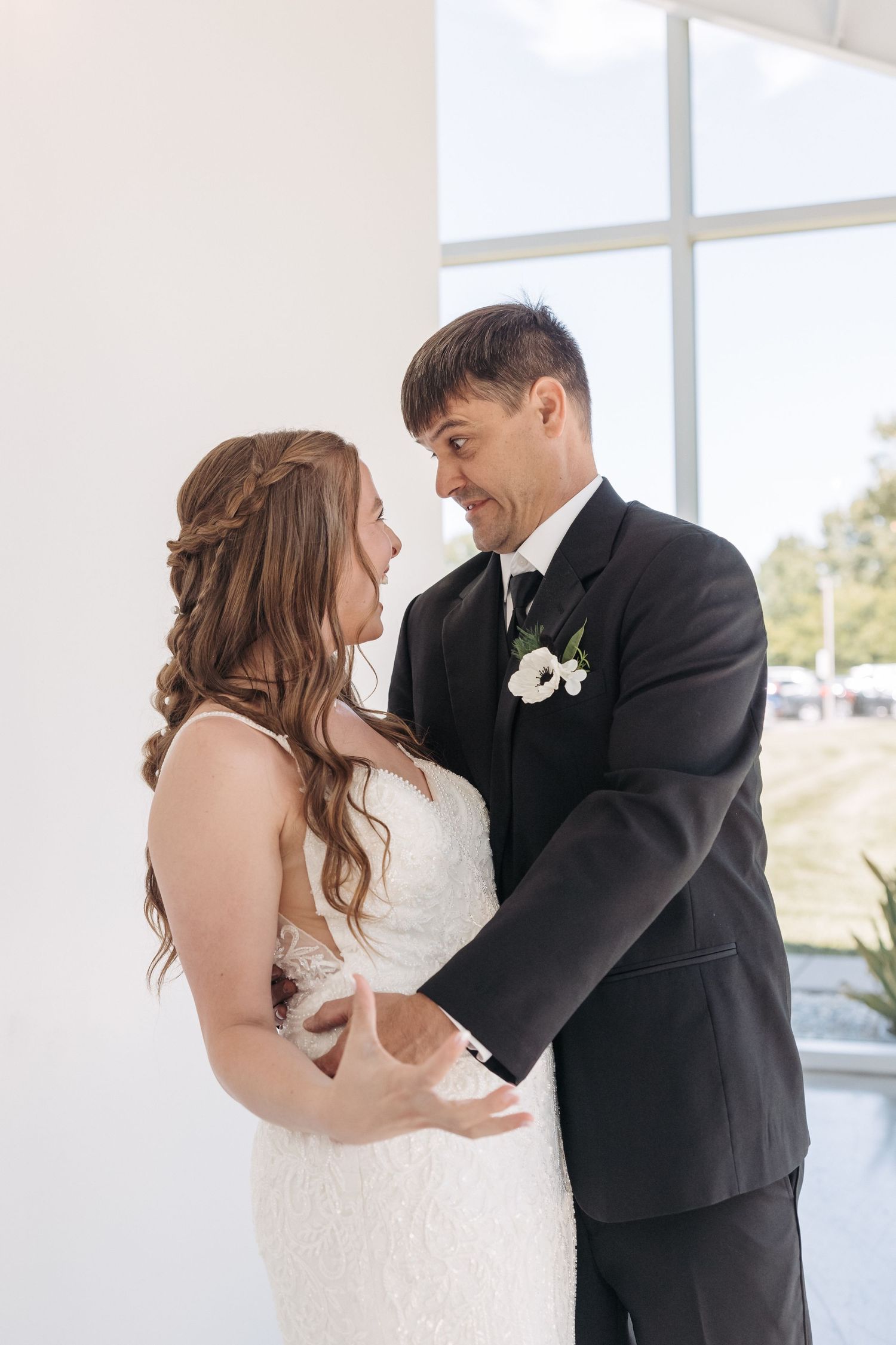 Romantic wedding couple sharing an intimate moment in a bright indoor setting.
