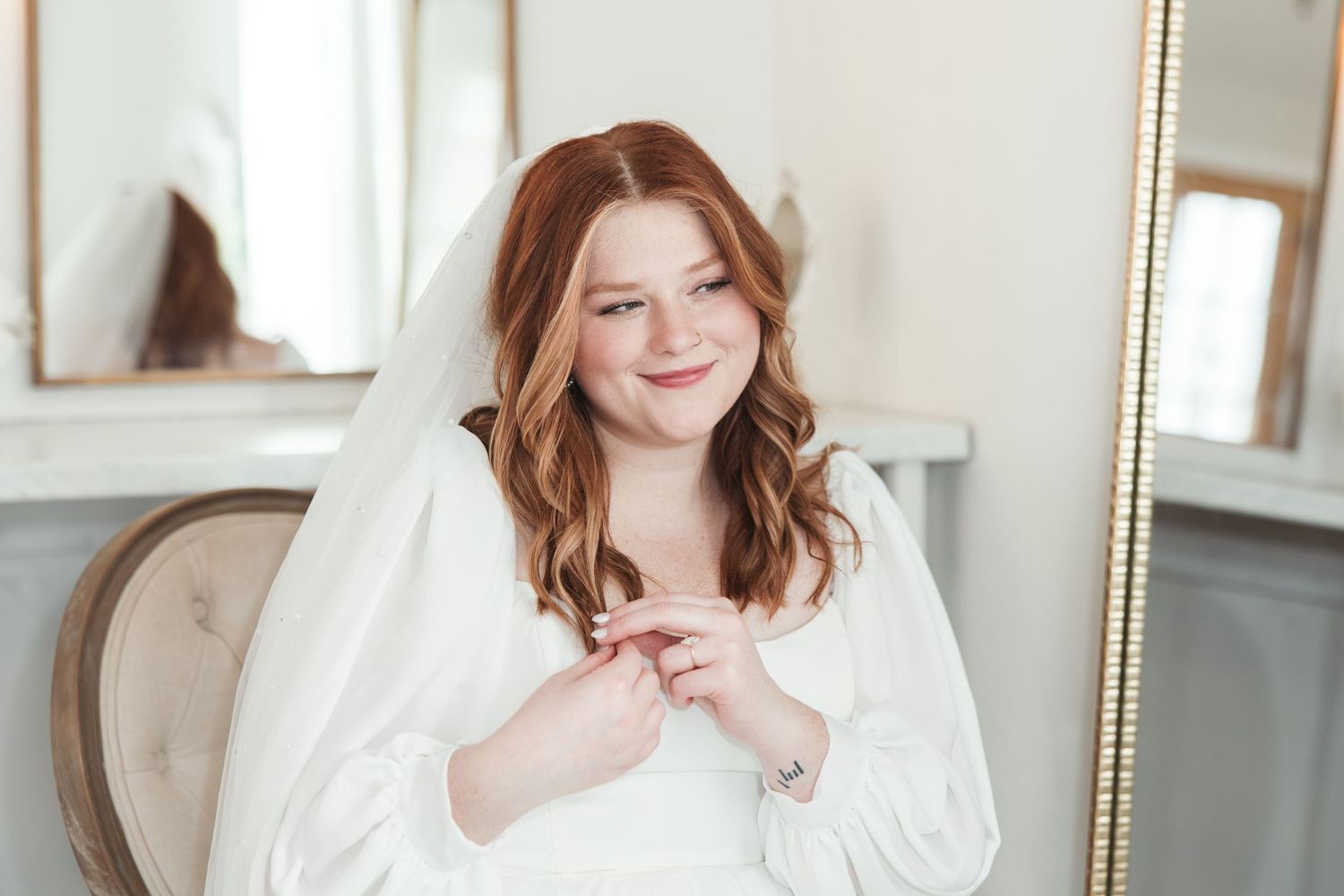 Bride smiling in white robe during wedding preparations in elegant room.