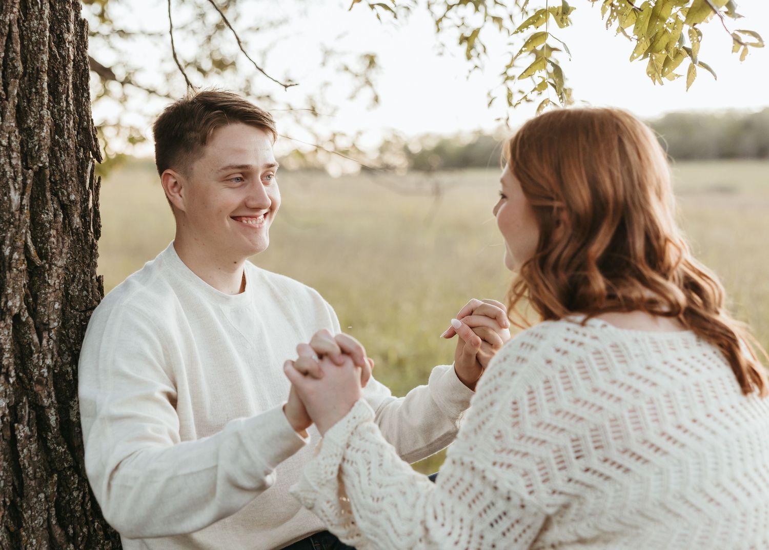 Two people share a joyful moment while sitting on a stone wall outdoors.