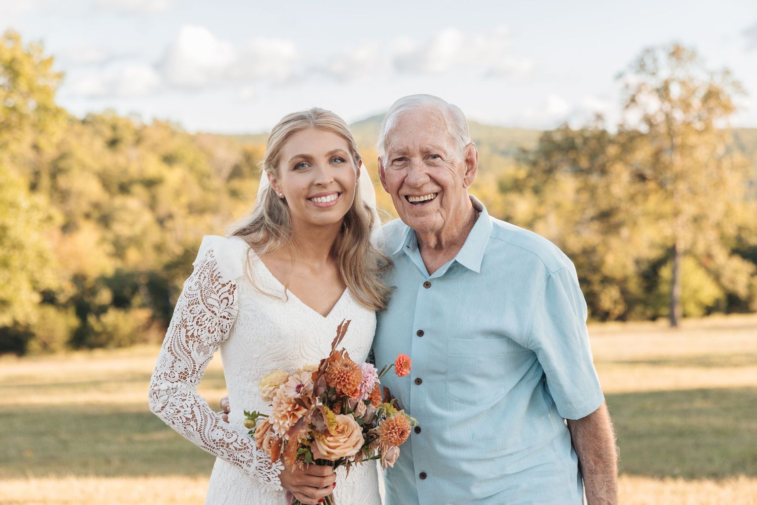 Sweet outdoor wedding portrait with soft golden lighting and autumn florals.