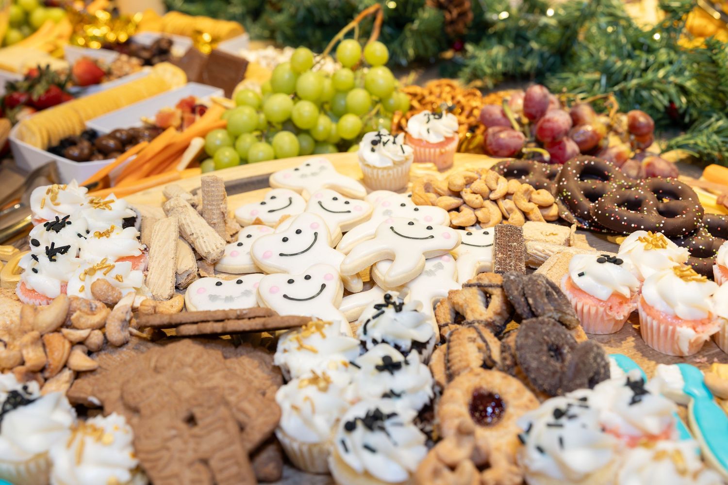 Festive dessert table with cookies, grapes, and various sweet treats arranged beautifully.