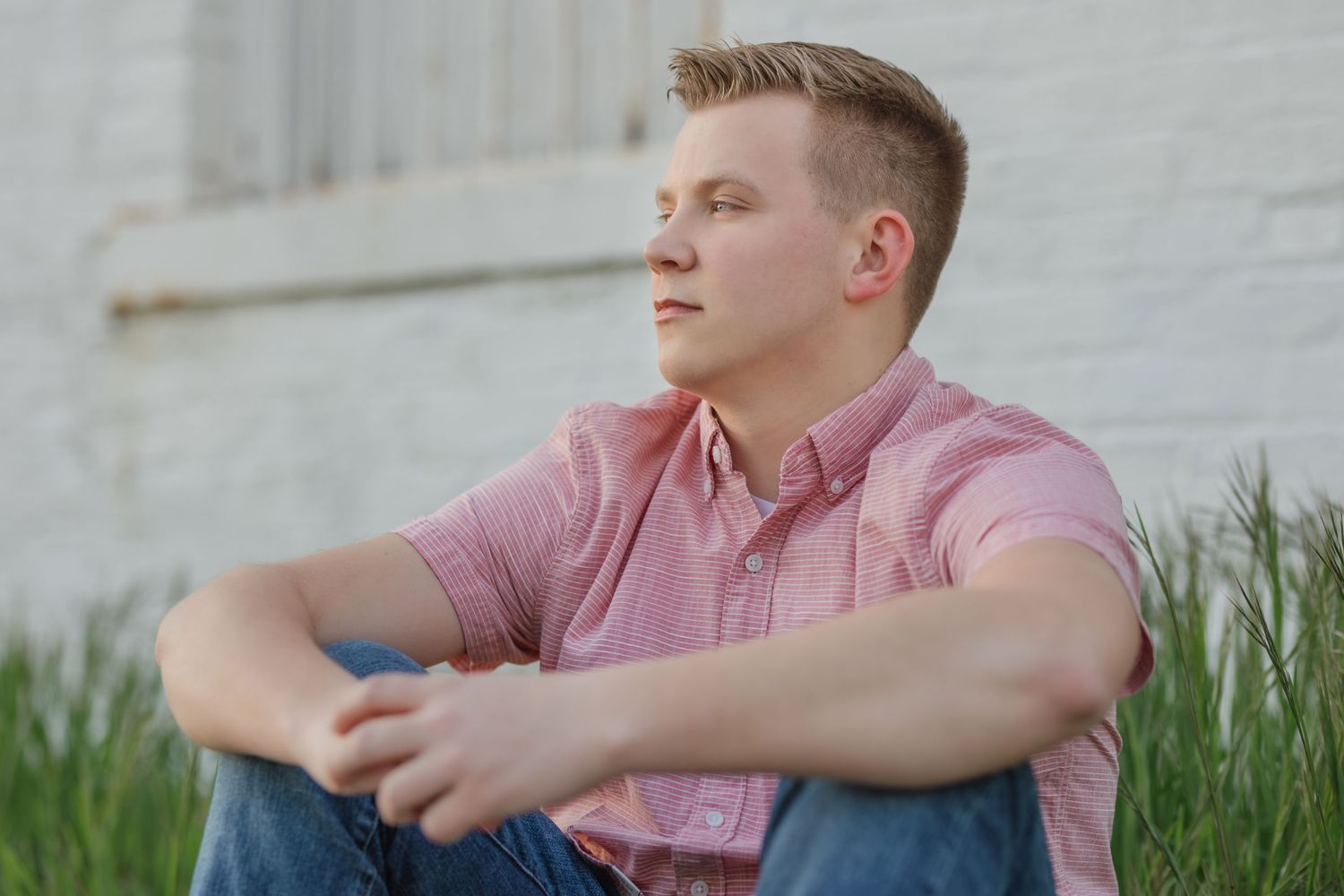 Outdoor portrait in pink shirt sitting in grass with natural lighting.
