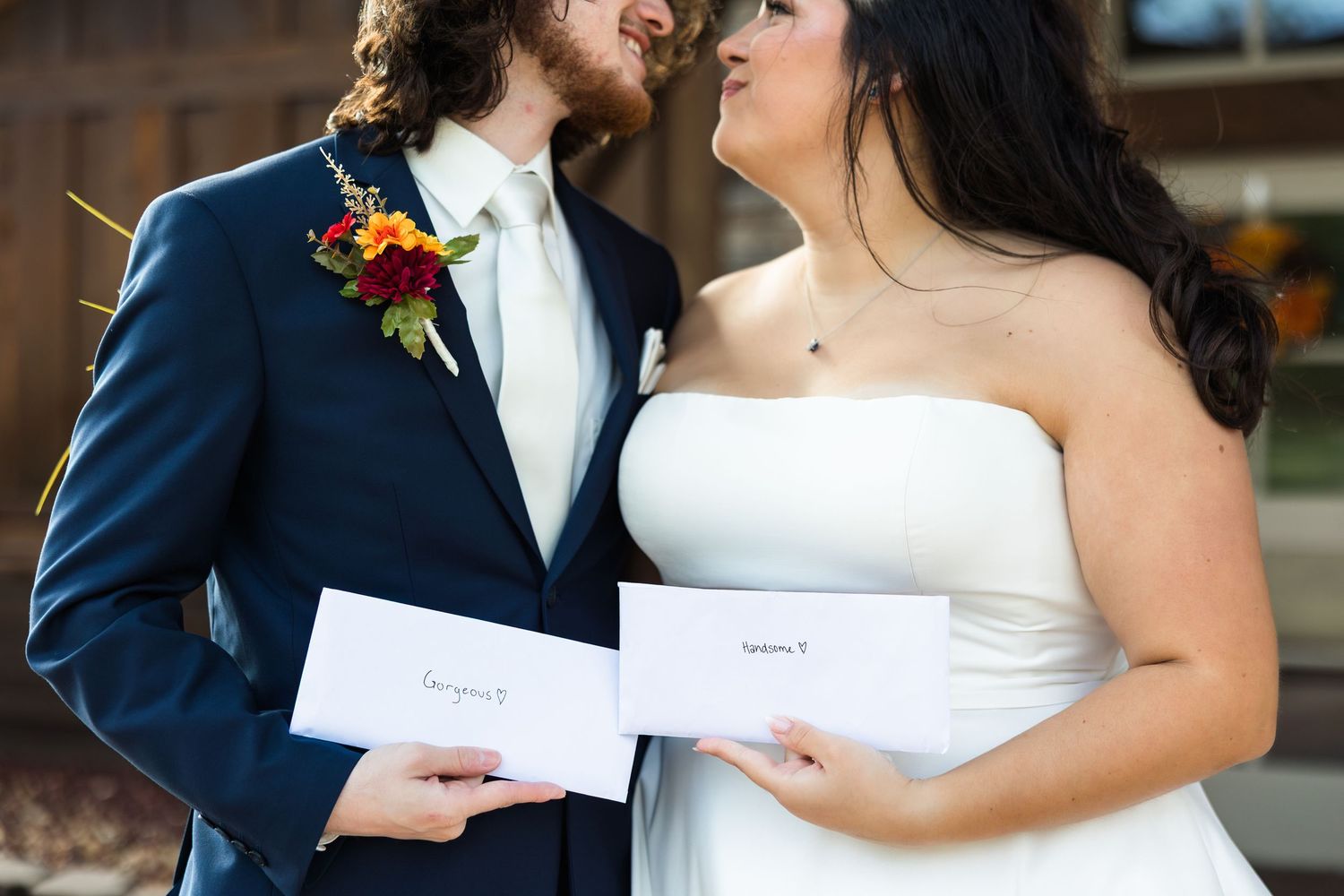 A couple in wedding attire shares a tender moment while holding papers during their ceremony.