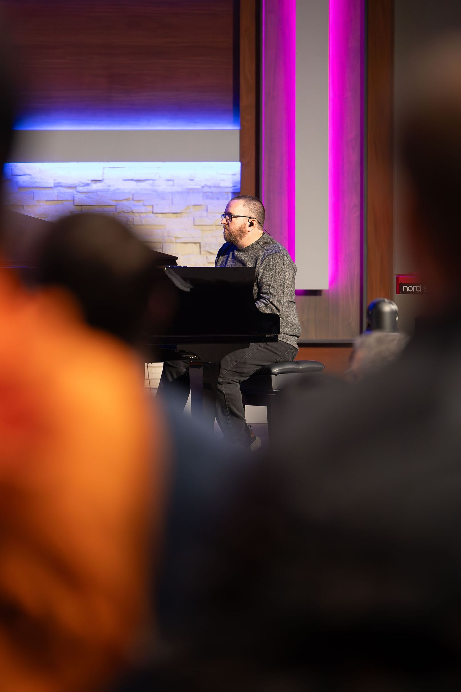 A musician playing piano on stage with colorful lighting effects.