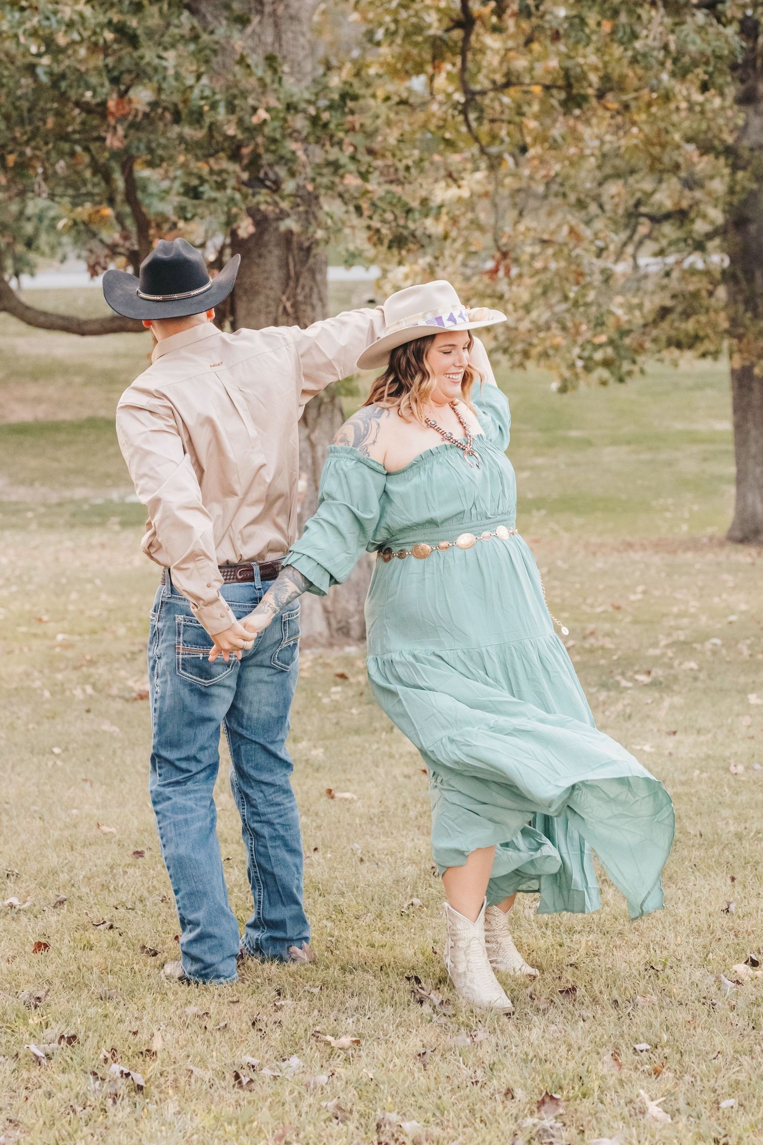 Couple in western attire dancing outdoors with the woman wearing a flowing mint green dress.