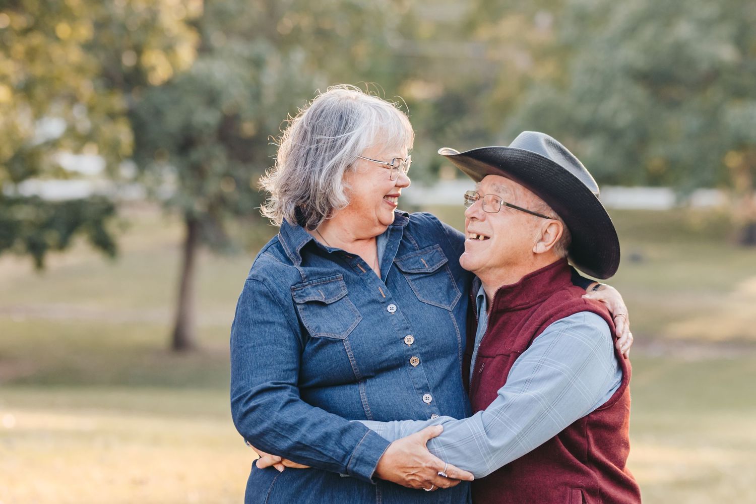 An older couple embraces and shares a joyful moment outdoors.