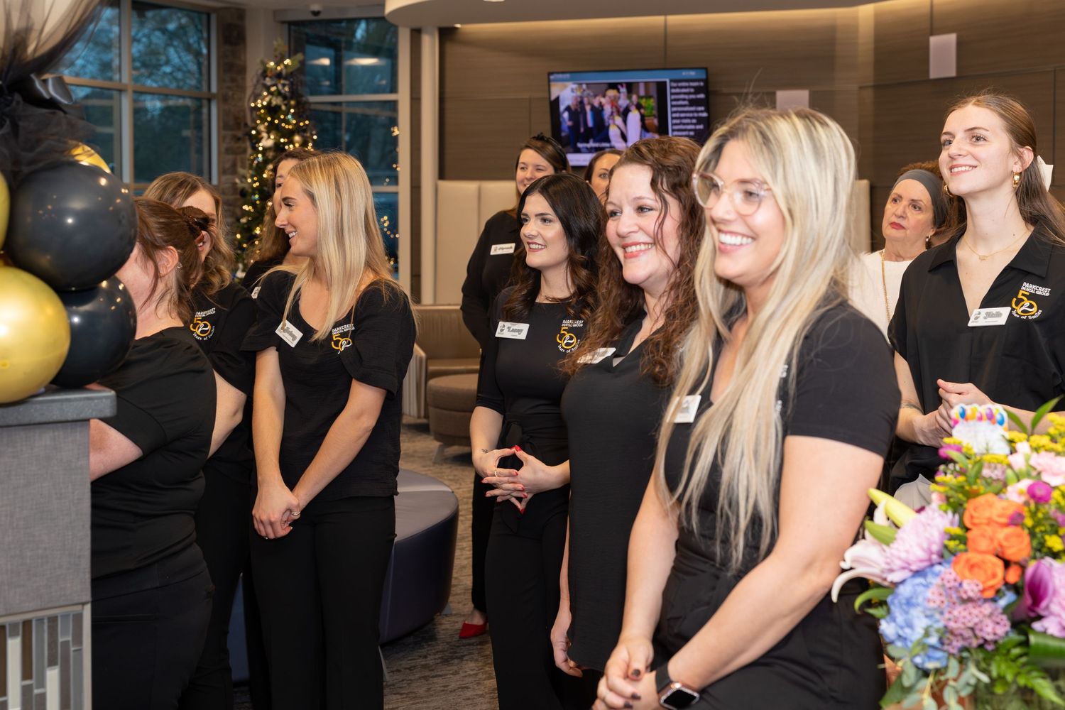 Professional gathering with team members in black attire and festive balloon decorations.