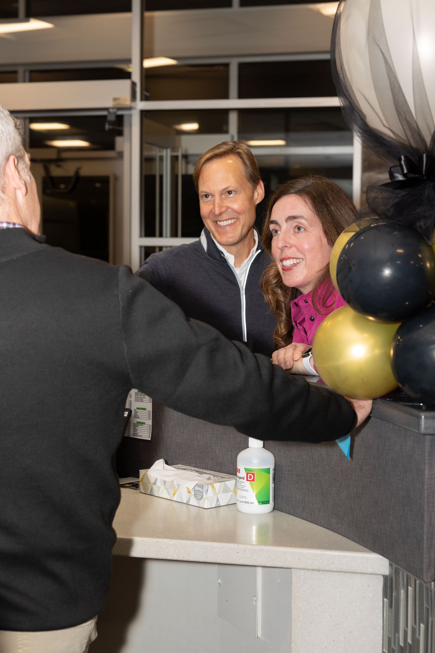 People chatting near decorative balloons at office celebration event.