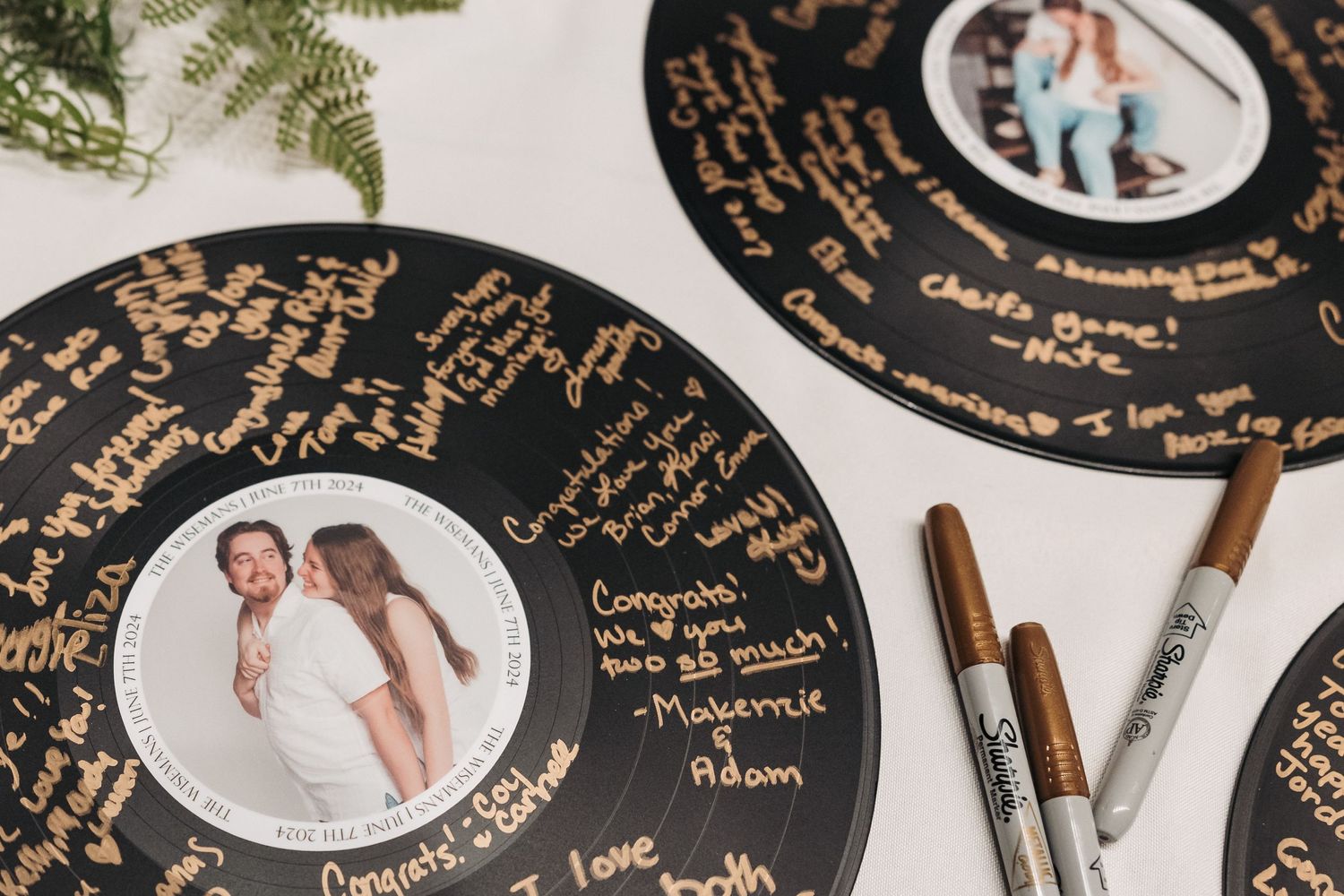 Vinyl record wedding guestbook with gold signatures and photo in center.