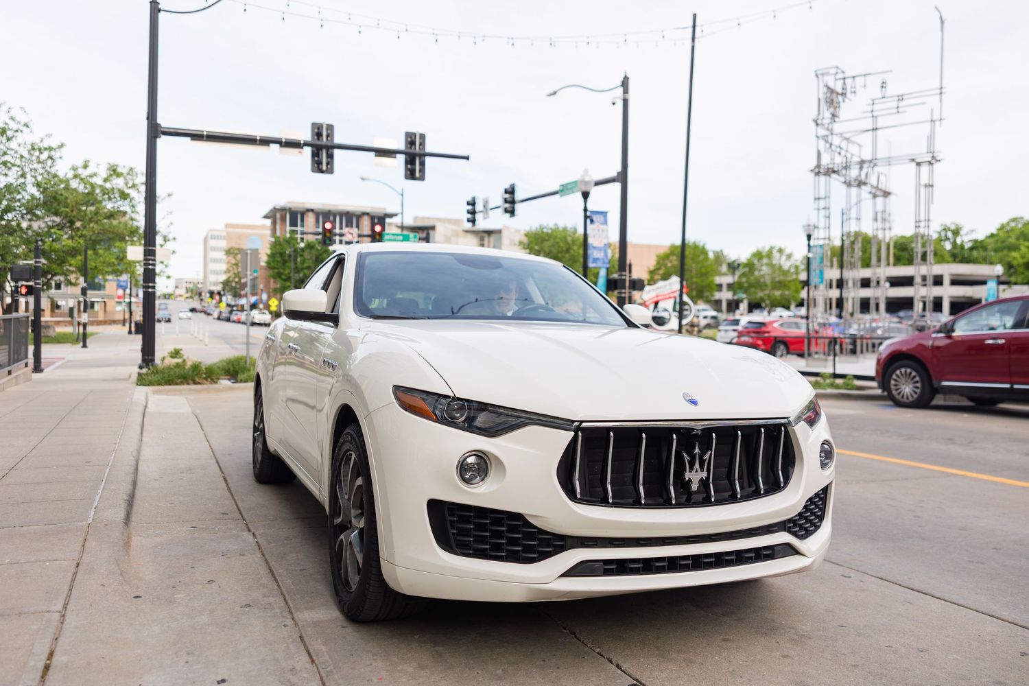 White Maserati Levante luxury SUV parked on urban street corner on sunny wedding day.