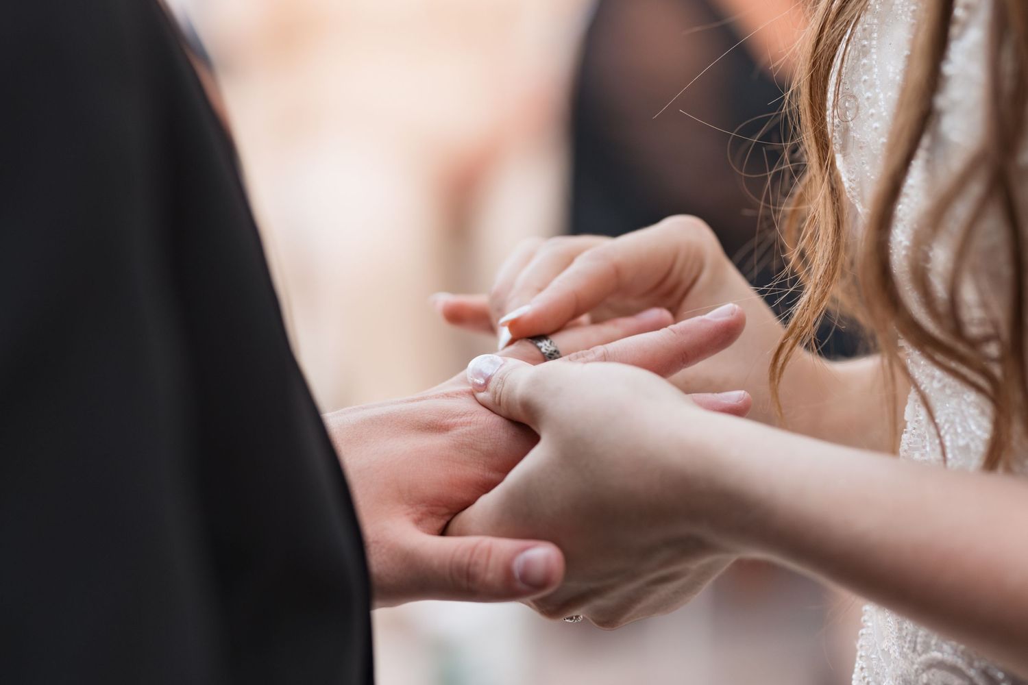 Close-up of hands exchanging wedding rings during a ceremony.