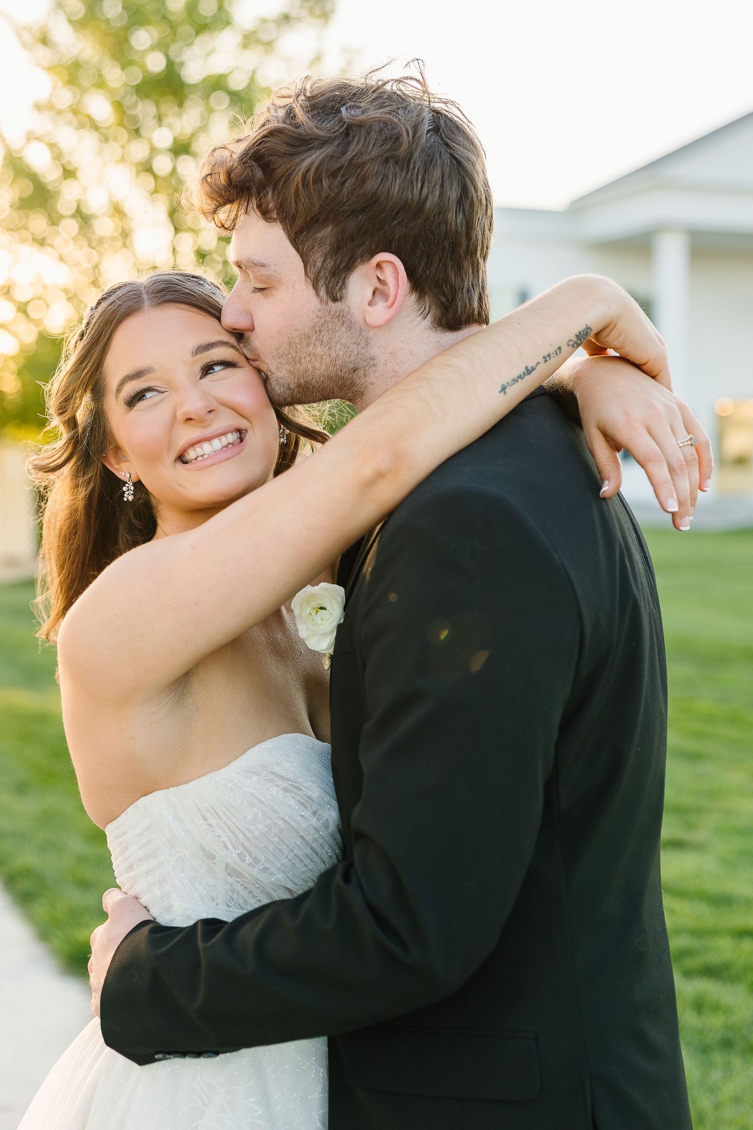 Newlywed couple embracing in sweet candid moments during golden hour outdoor photo session in garden setting.