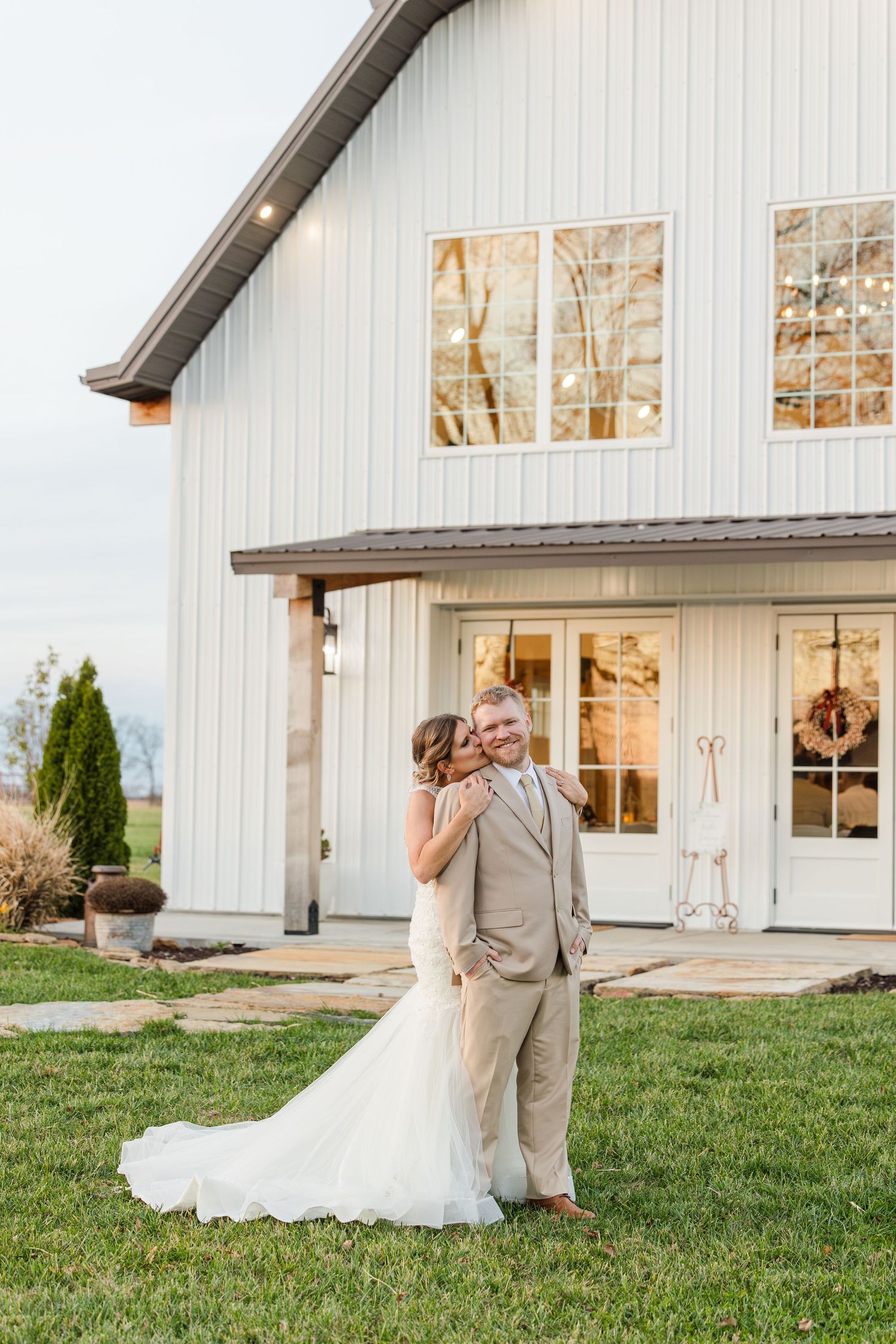 A romantic moment captured outside a modern white barn wedding venue.