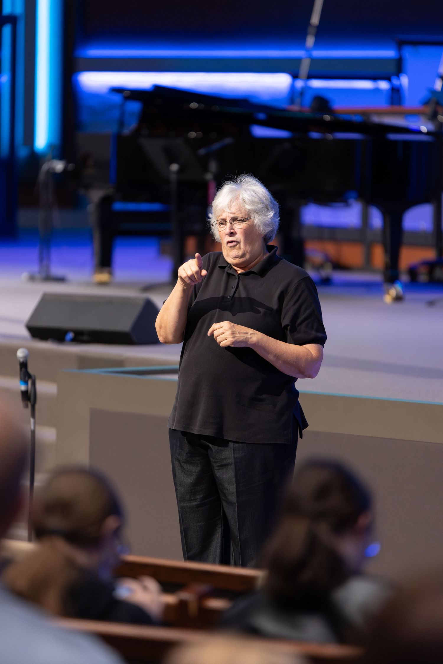 A speaker in black attire addresses the congregation from the church stage.