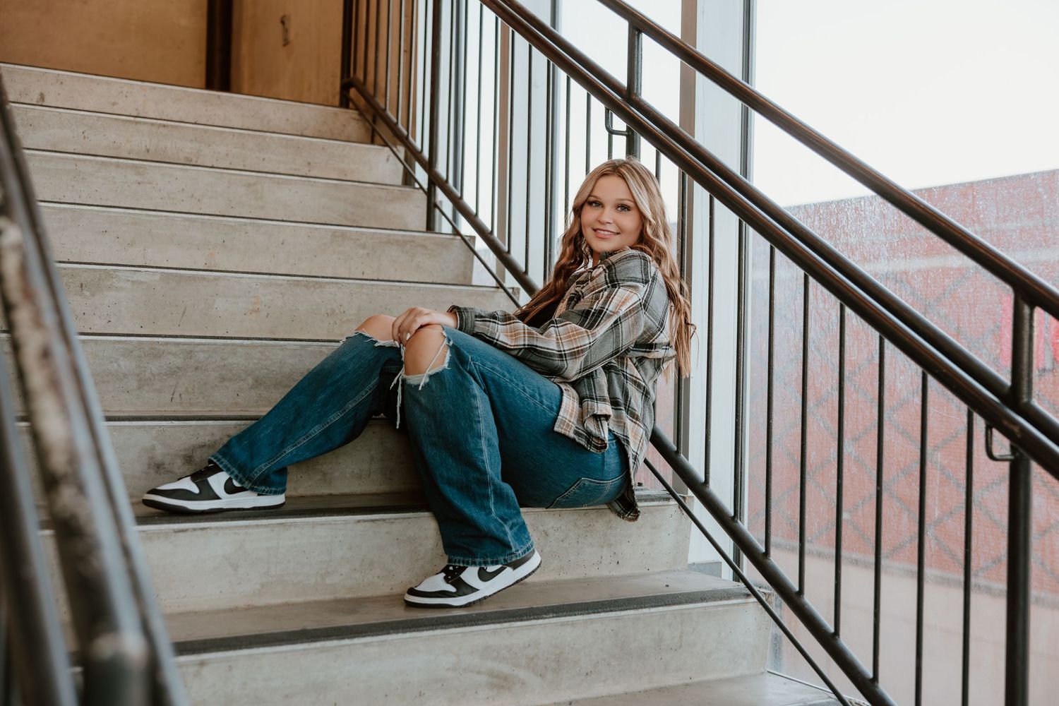 Casual style portrait on concrete stairs wearing plaid shirt and distressed denim.