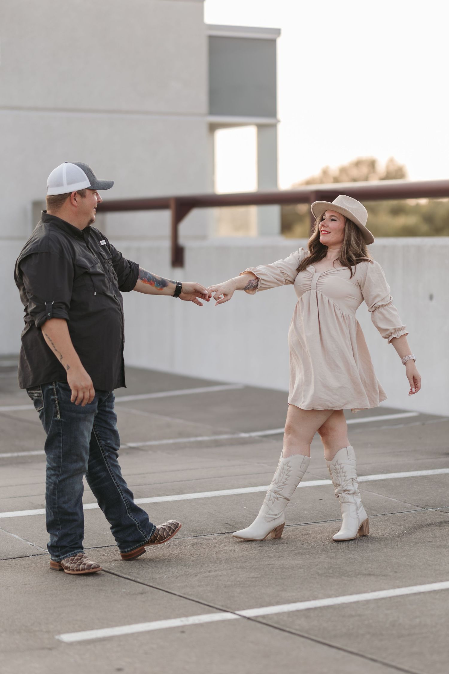 Couple in contrasting outfits dancing in an urban setting.
