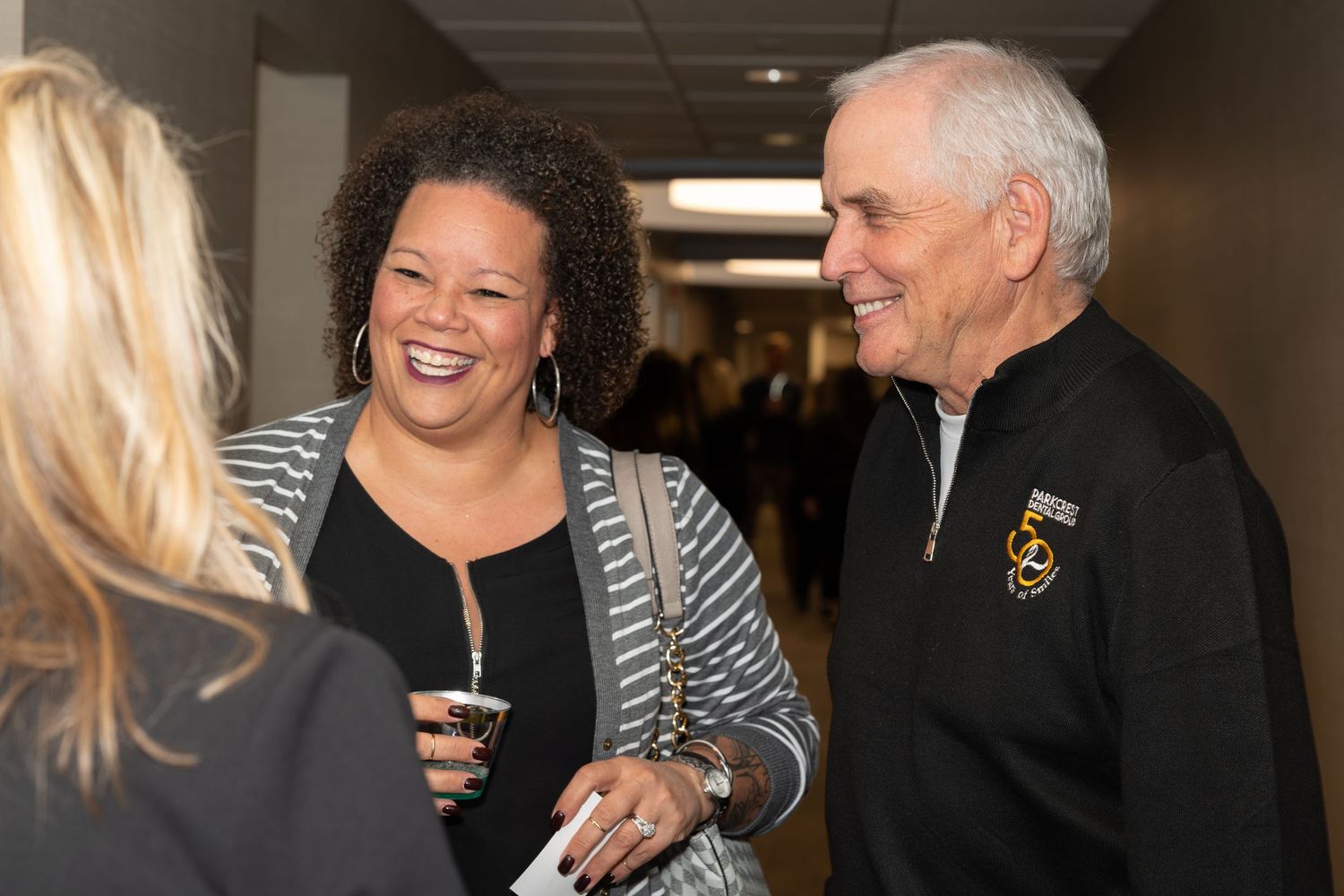 People sharing a laugh during a social gathering in an office hallway.