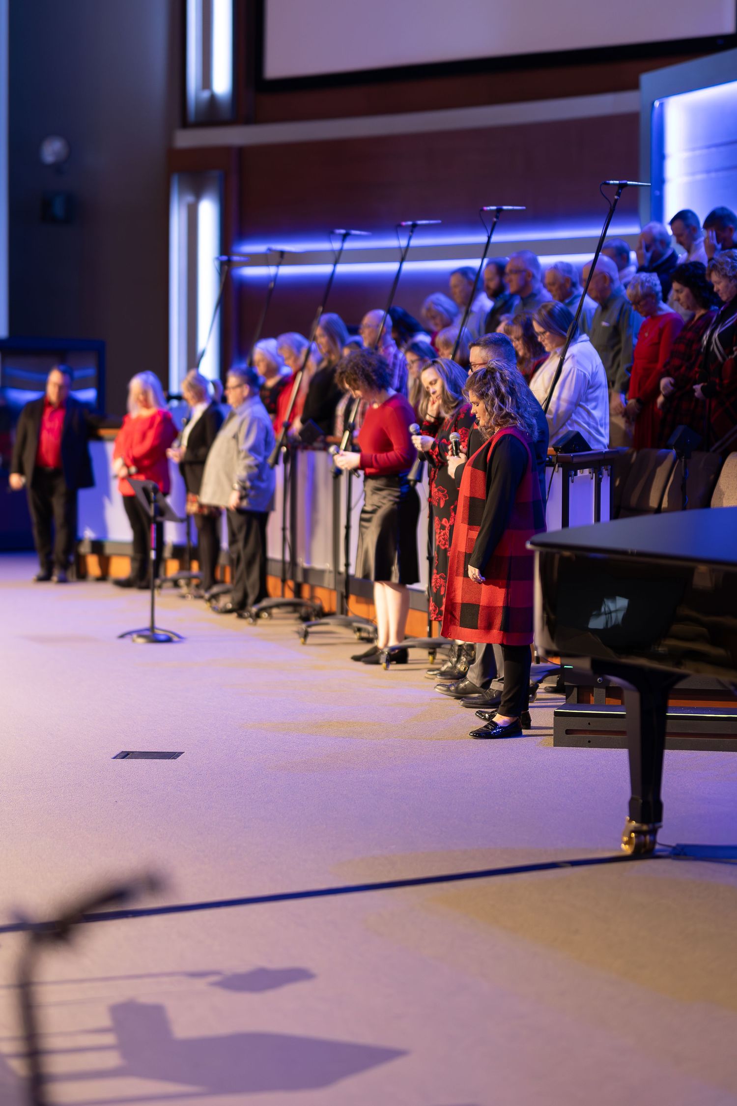 Choir stands in formation with microphones during church service performance.