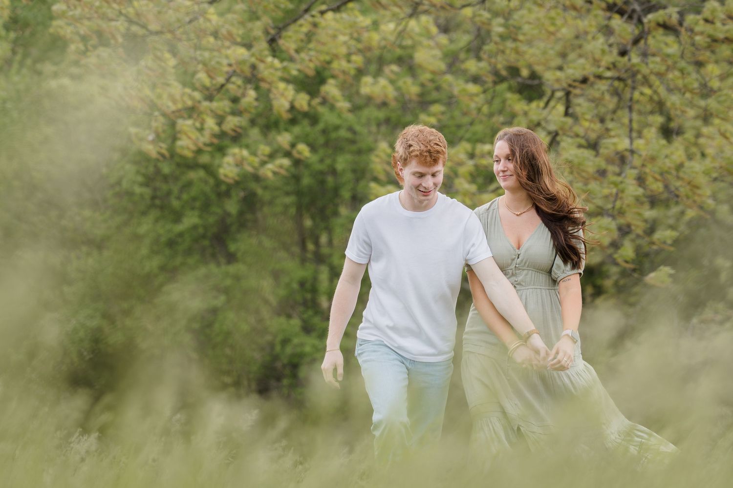 A romantic couple walks hand in hand through a lush garden setting on a bright spring day.