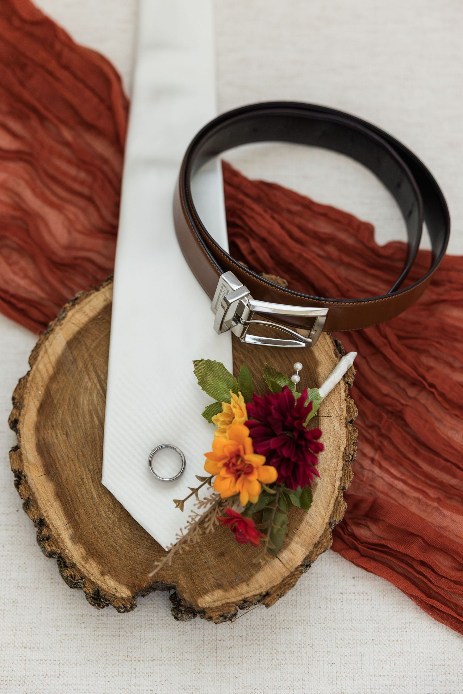 Wedding ring and flowers arranged on a rustic wood slice in a creative progression photo series.