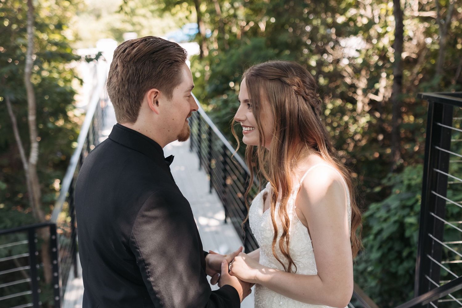 Intimate moment between newlyweds on wooden bridge surrounded by nature.