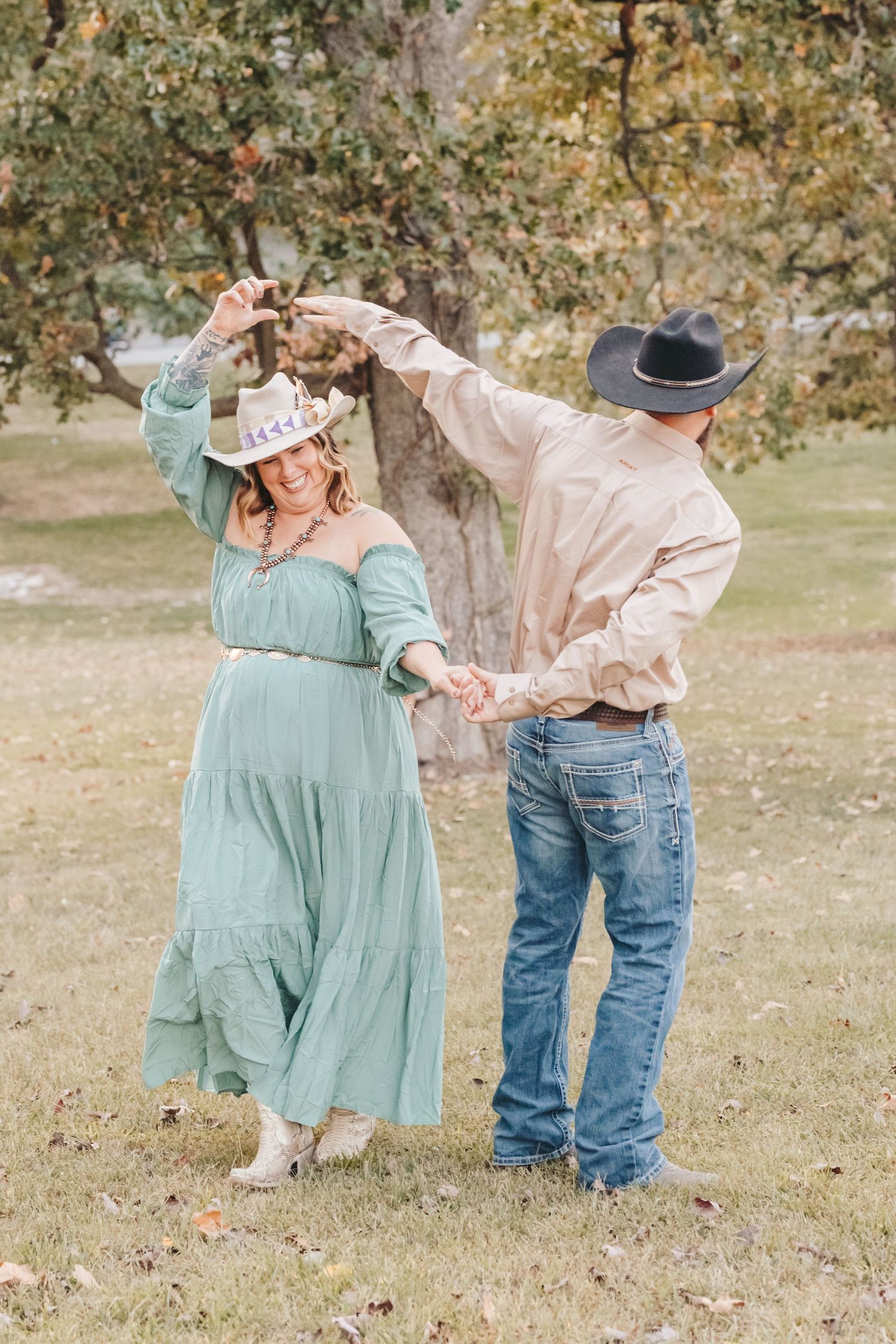 Couple dancing outdoors wearing western attire and cowboy hats.