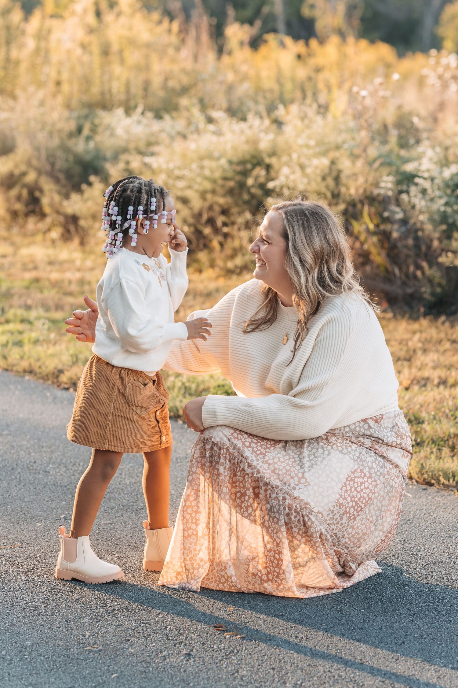 A heartwarming outdoor moment between a woman in white sweater and young child in autumn sunlight.