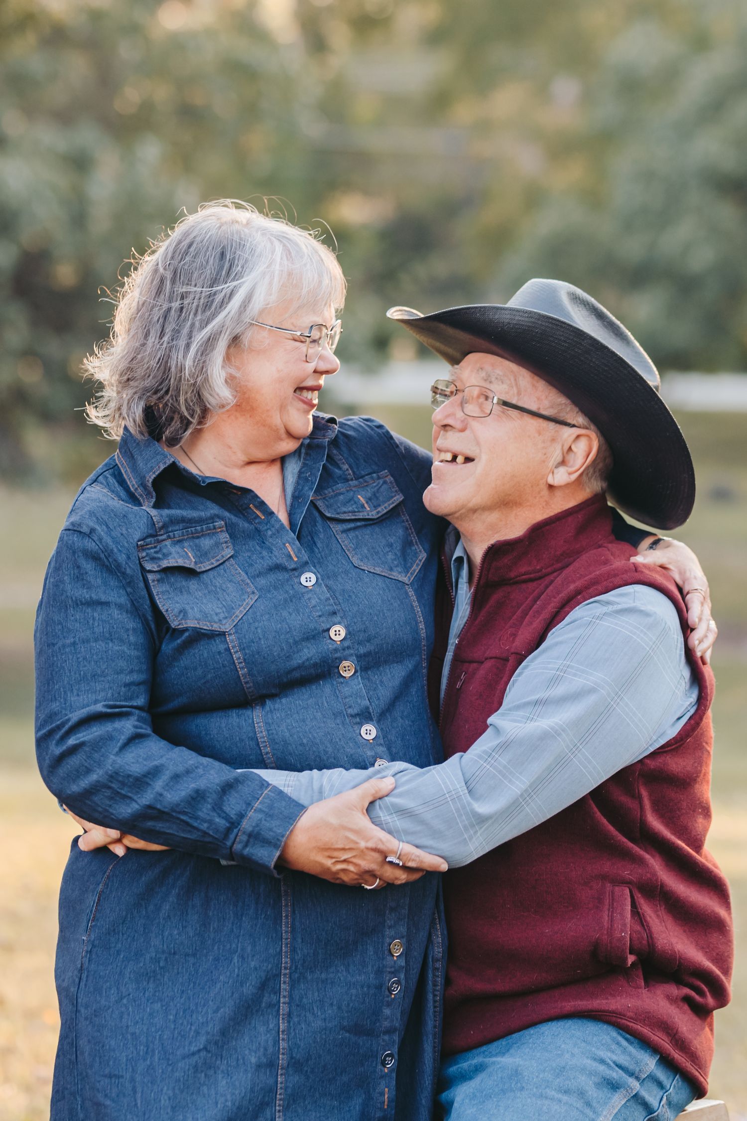 A tender moment between a couple in casual western wear sharing laughter outdoors.