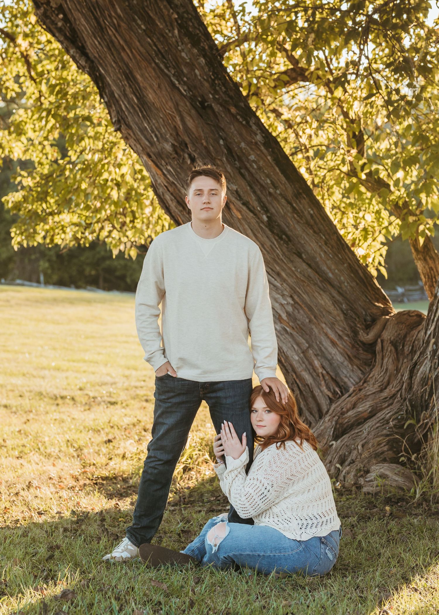 A relaxed outdoor portrait session against a rustic tree backdrop at sunset.