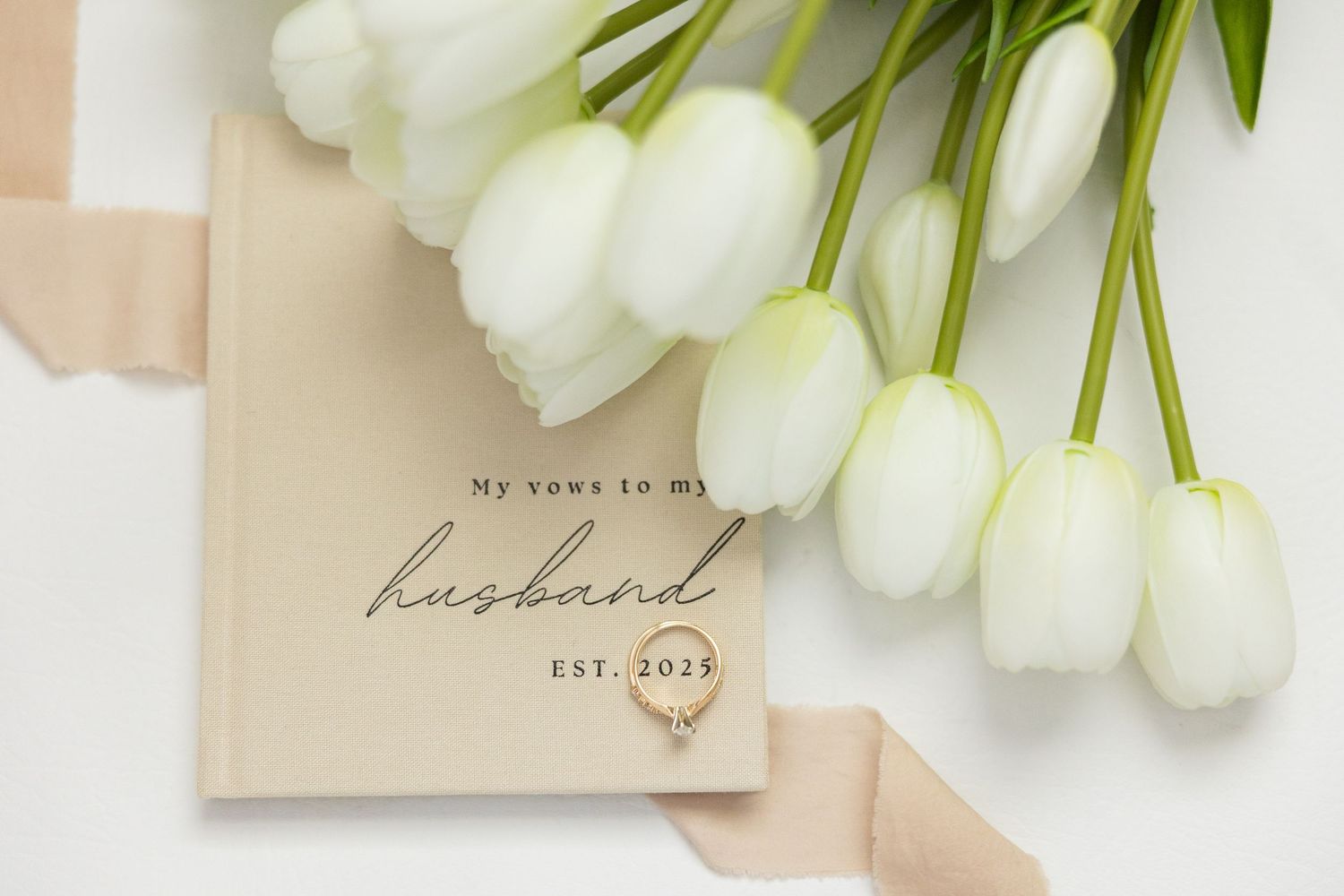 Elegant white tulips rest beside minimalist romantic wedding text art prints in neutral beige tones.