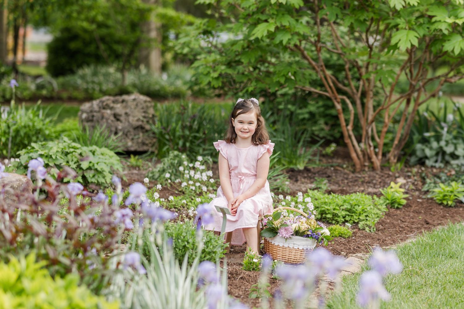 A series of spring garden photos shows someone in pink sitting among blooming flowers and lush greenery in a peaceful setting.
