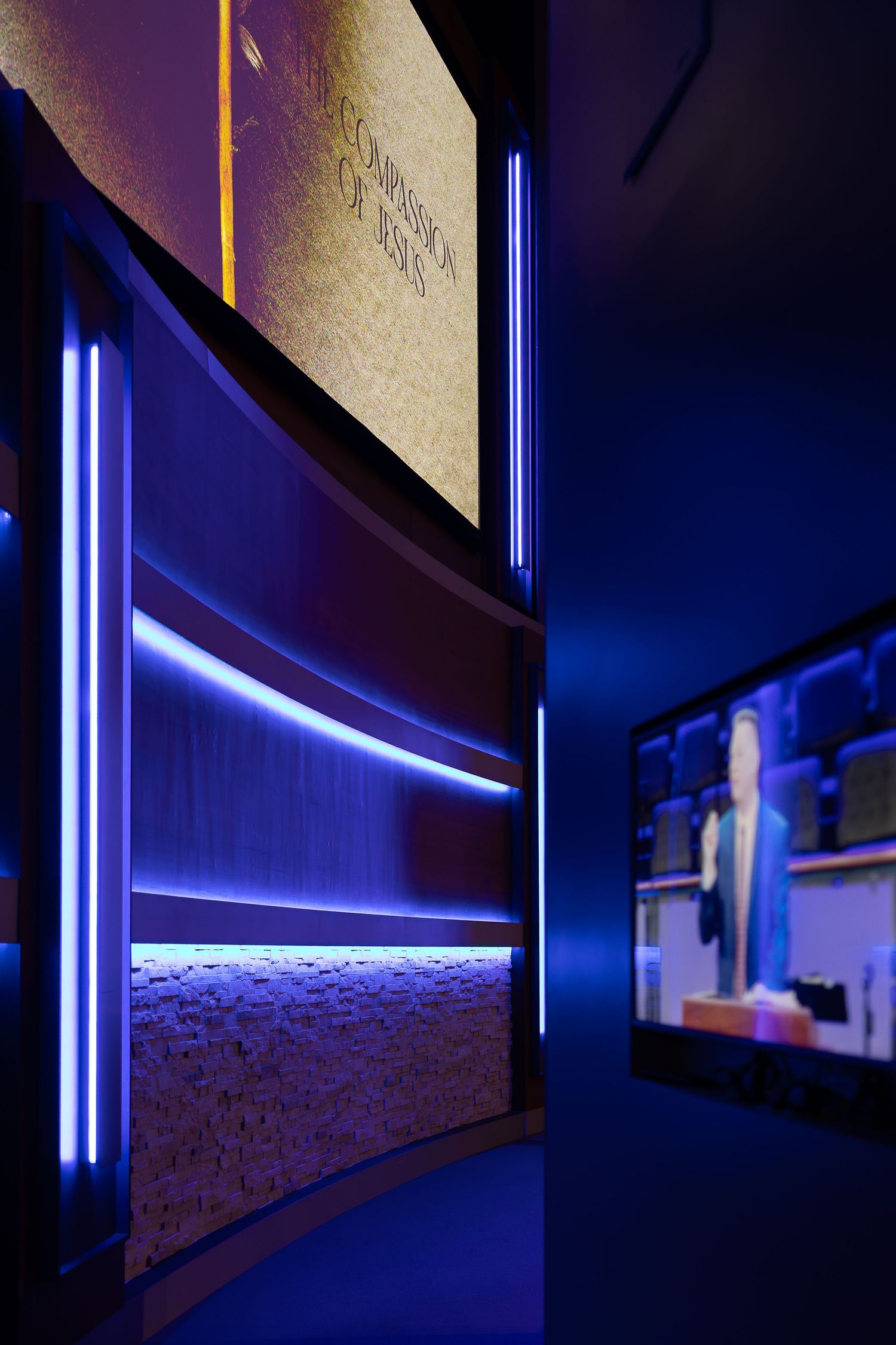 Curved wall installation with vertical blue LED light strips and textured surface panels.