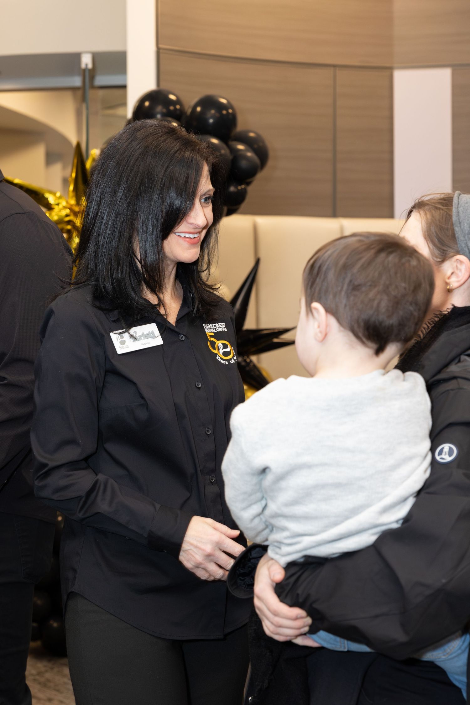 Staff member in black uniform interacting warmly with young child at corporate event.